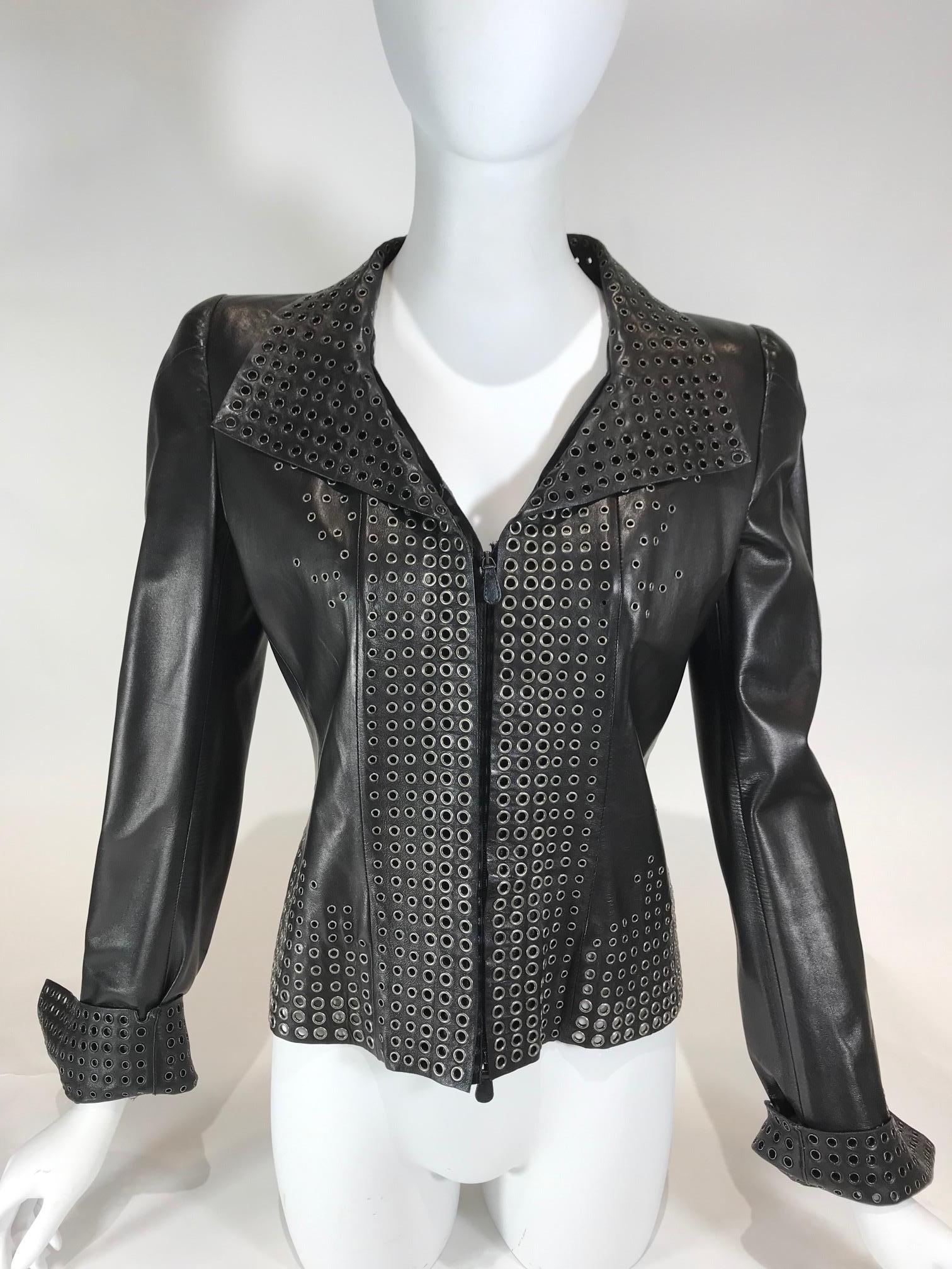 Black leather. Silver-tone hardware. Zipper closure at front. Collared. Featuring grommet design throughout.