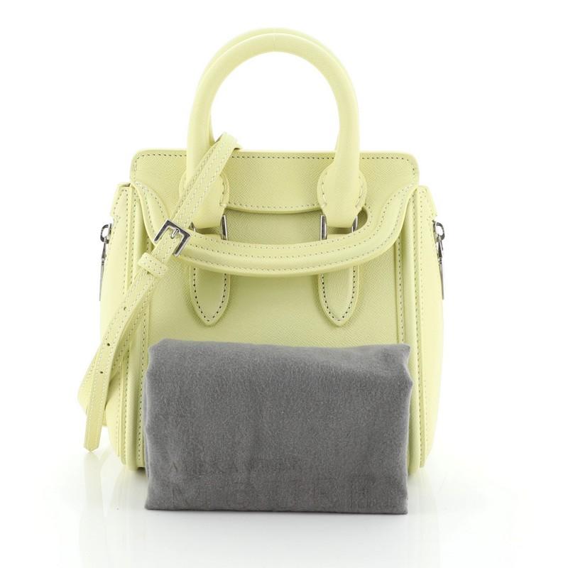 This Alexander McQueen Heroine Tote Leather Mini, crafted in yellow leather, features dual rolled leather handles, oversized side zipper details, embossed logo at the center, and silver-tone hardware. Its flap closure opens to a gray suede interior