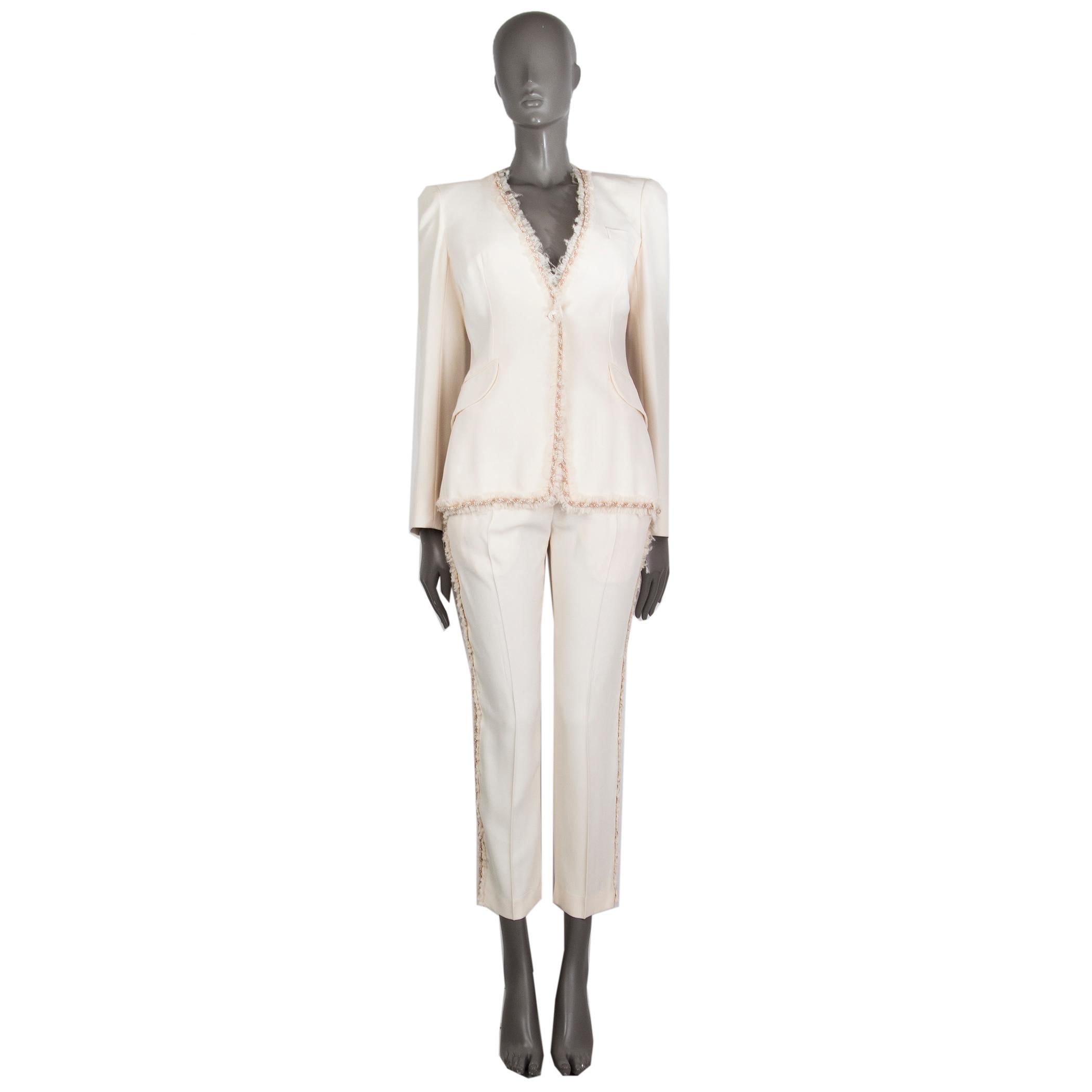 100% authentic Alexander McQueen collarless blazer in light cream acetate (45%), viscose (45%), and silk (10%). With beaded braid and fray trimmings, two flap pockets on the sides, buttoned cuffs, and slit on the back. Closes with nacre button on