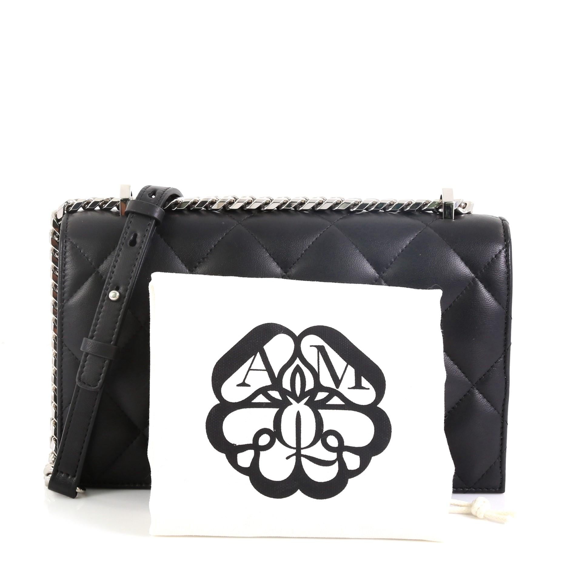 This Alexander McQueen Jewelled Flap Satchel Quilted Leather Medium, crafted in black quilted leather, features chain link and leather strap, skull and crystal embellished knuckle duster, and silver-tone hardware. Its magnetic snap button closure