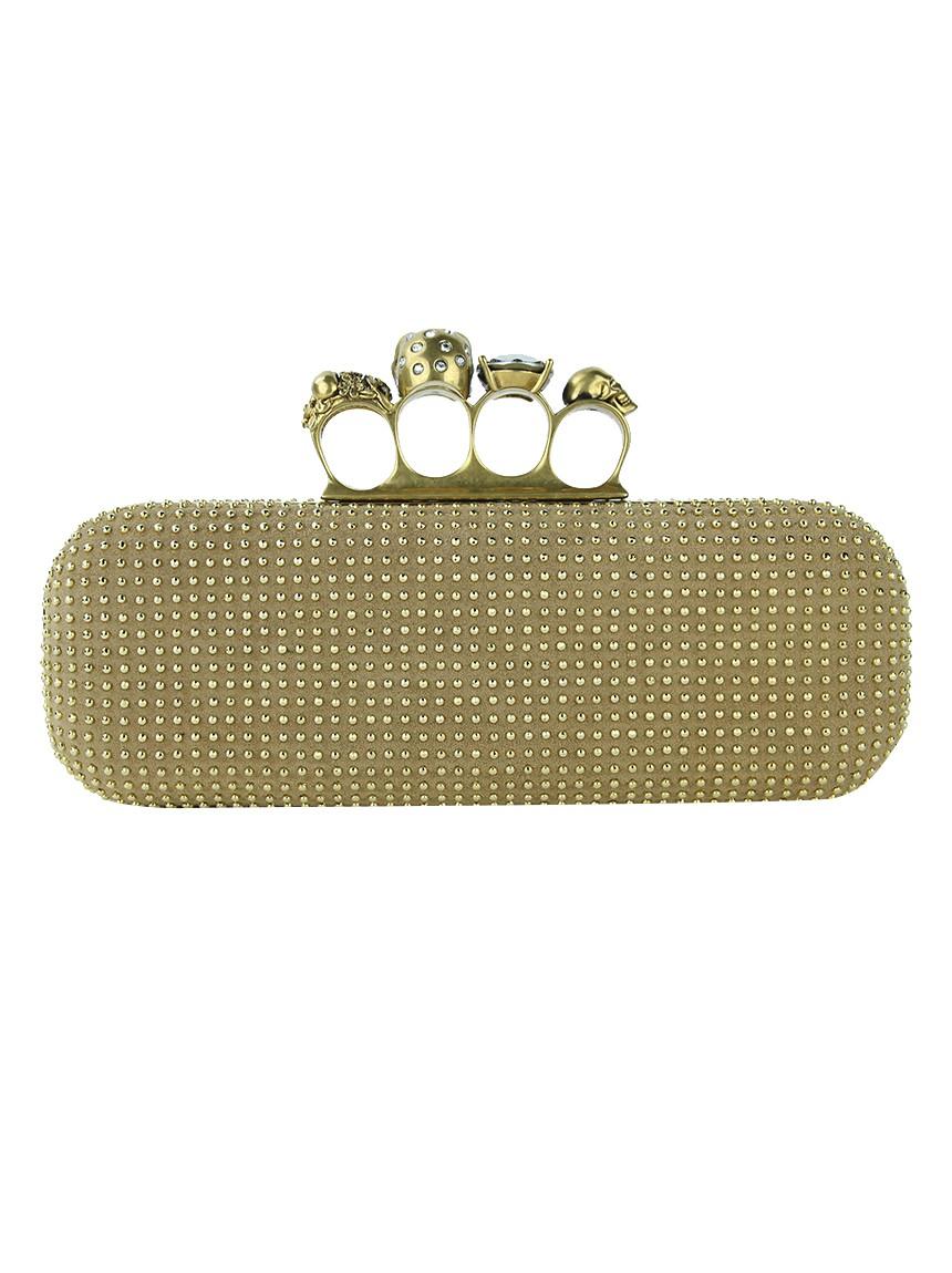 ALEXANDER MCQUEEN
	
Alexander Mcqueen Knuckle Duster Gold Original Clutch made in beige suede with gold micro rivet application. It features a structured rectangular design with rounded edges, four finger spacings with skull and black synthetic