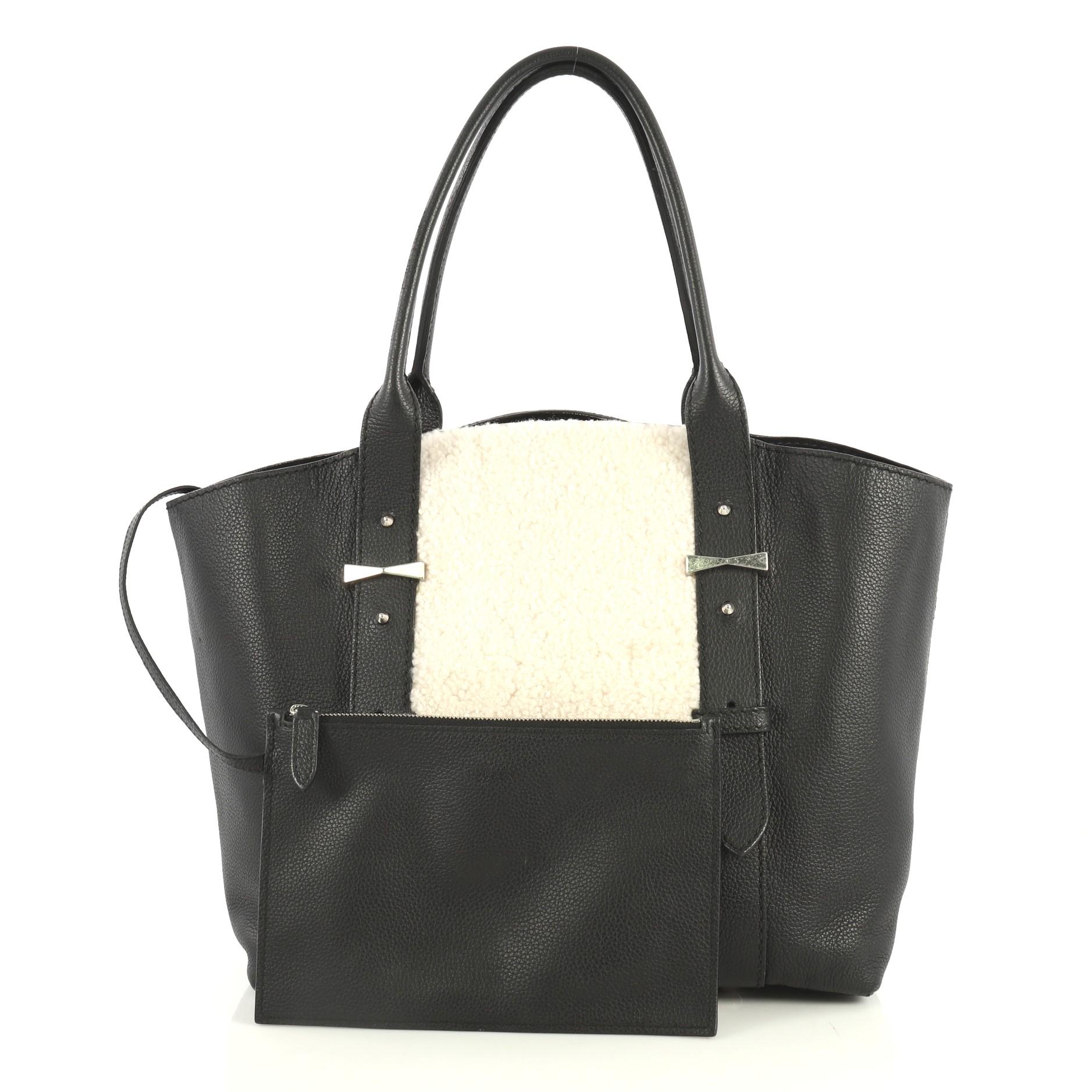 This Alexander McQueen Legend Tote Shearling with Leather Medium, crafted in black leather with white shearling, features dual rolled leather handles with belted leather details, protective base studs and silver-tone hardware. Its wide top opening
