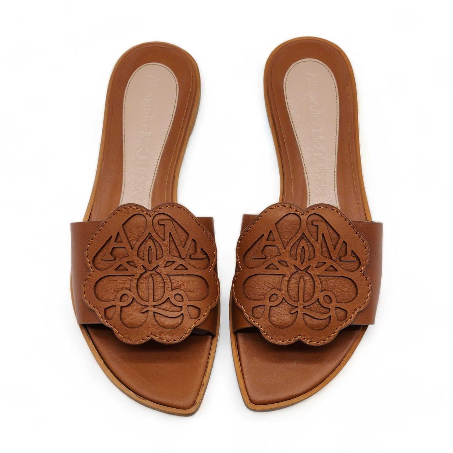 Sandalo slide in pelle di vitello marrone con logo McQueen sulla parte superiore. Il sandalo ha una suola asimmetrica in morbida pelle.

Informazioni aggiuntive:
Materiale: 100% pelle di vitello
Colore: marrone
Taglia: 6 US
Codice prodotto:
