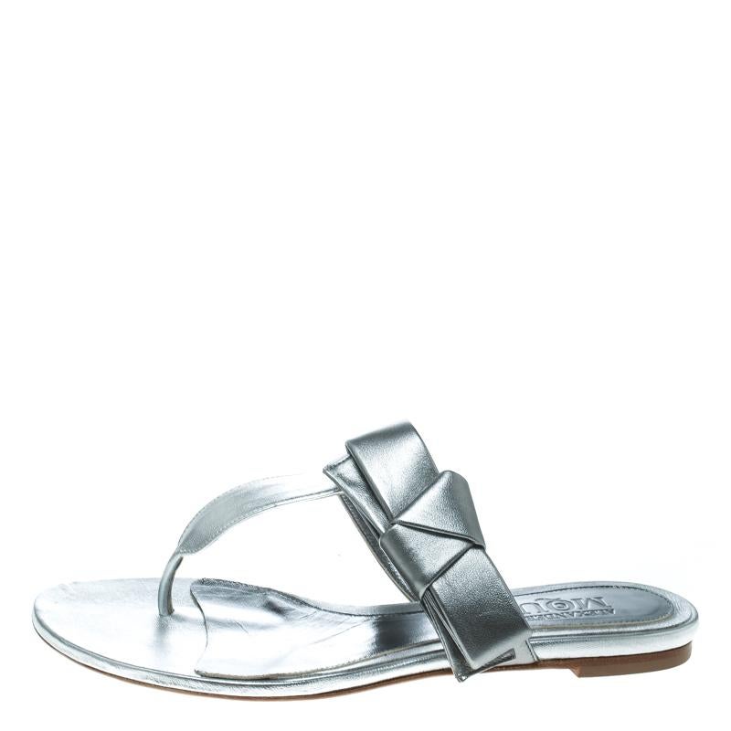 Let your feet rejoice at the sight of these sandals from Alexander McQueen! The metallic silver sandals are crafted from leather and feature a thong design. They've been styled with bows on the straps and come equipped with comfortable