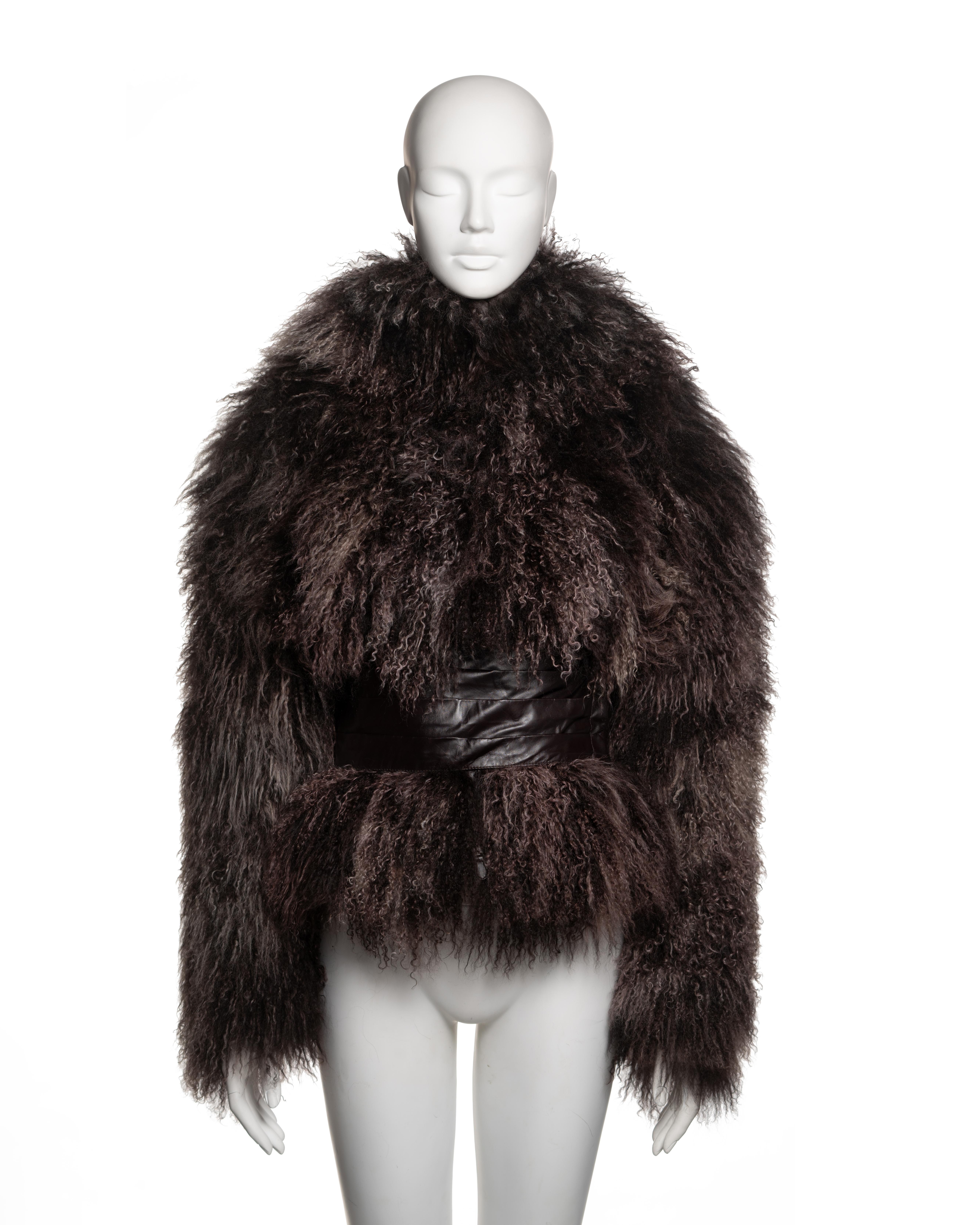 This Alexander McQueen jacket from the Fall-Winter 2004 collection is constructed from dark brown Mongolian lamb fur, enveloping the entire silhouette with a voluminous, sculptural effect. The design features a fully integrated hood that extends