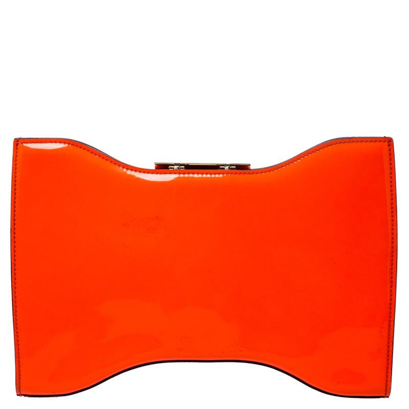 This elegant clutch from Alexander McQueen is easy to carry without compromising on style. Crafted from neon orange leather, the clutch features a gold-tone metal lock on top. The interior is leather-lined and has a zip pocket.

Includes: Original