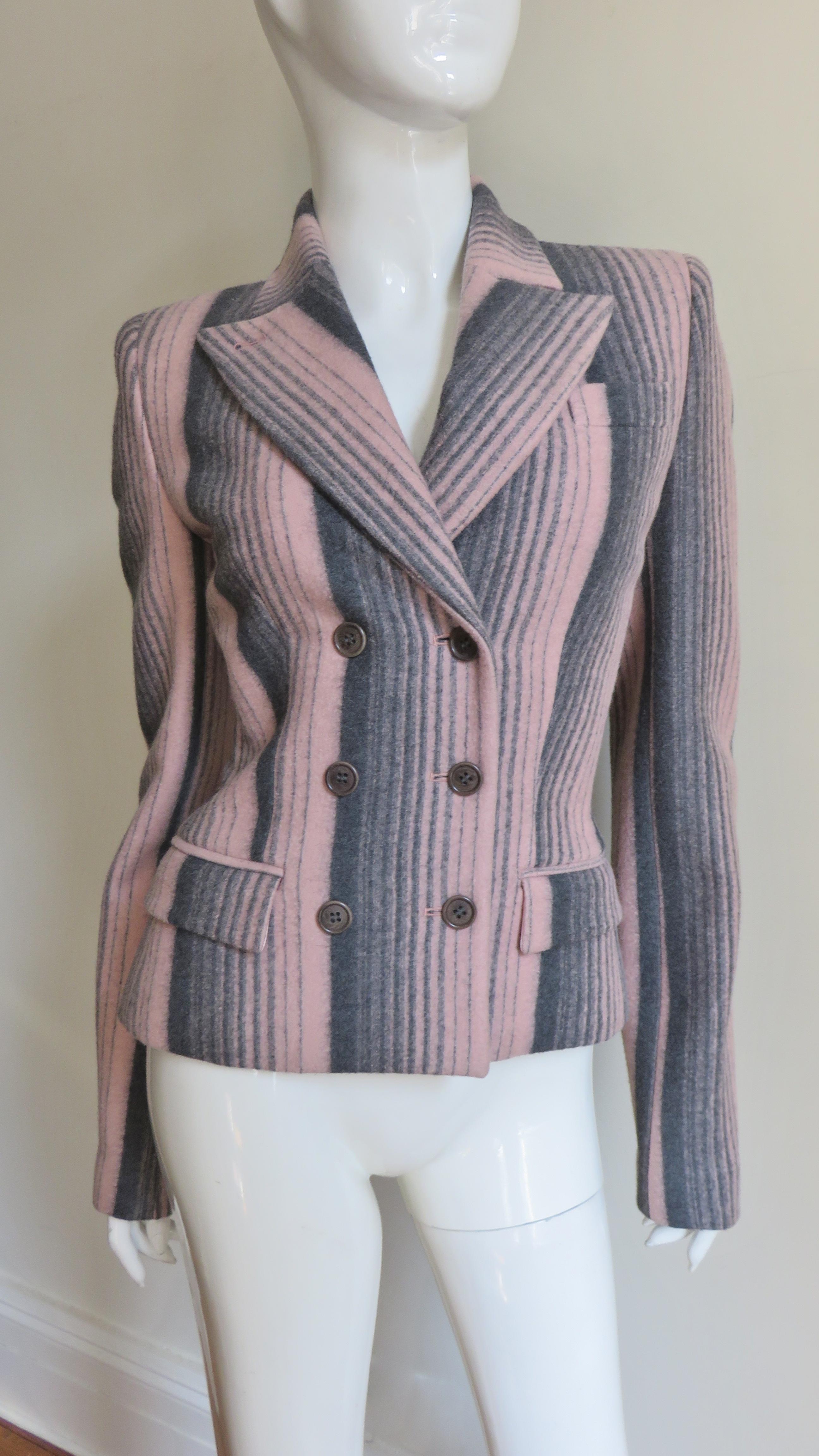 A grey and pink gradated striped wool jacket by Alexander McQueen.  It is double breasted with grey buttons at front and 3 at each cuff.  There is light shoulder padding, flap pockets at each front hip and a double vent in the back.  It is lined in