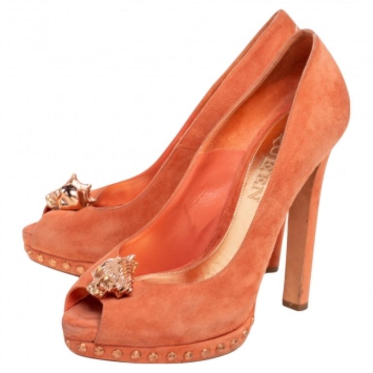Cette paire d'escarpins signée Alexander McQueen se caractérise par un design raffiné et une confection exquise. Confectionnés en daim orange, ces escarpins sont ornés d'un motif de tête de mort sur l'empeigne. Intemporelles et élégantes, elles sont