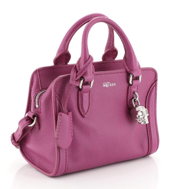 This Alexander McQueen Padlock Zip Around Tote Leather Mini, crafted from purple leather, features dual rolled handles and silver-tone hardware. Its zip closure opens to a black fabric interior with side zip and slip pockets. 

Estimated Retail