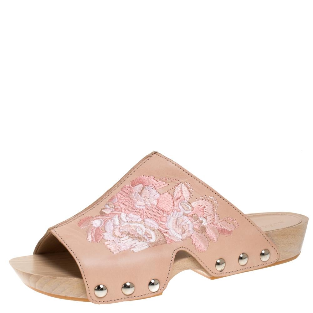 Add some elegant and feminine style with a unique touch to your day time wear collection with these Alexander McQueen wooden clogs. Constructed in peach leather along with a wooden base, these shoes are completed with floral embroidery and