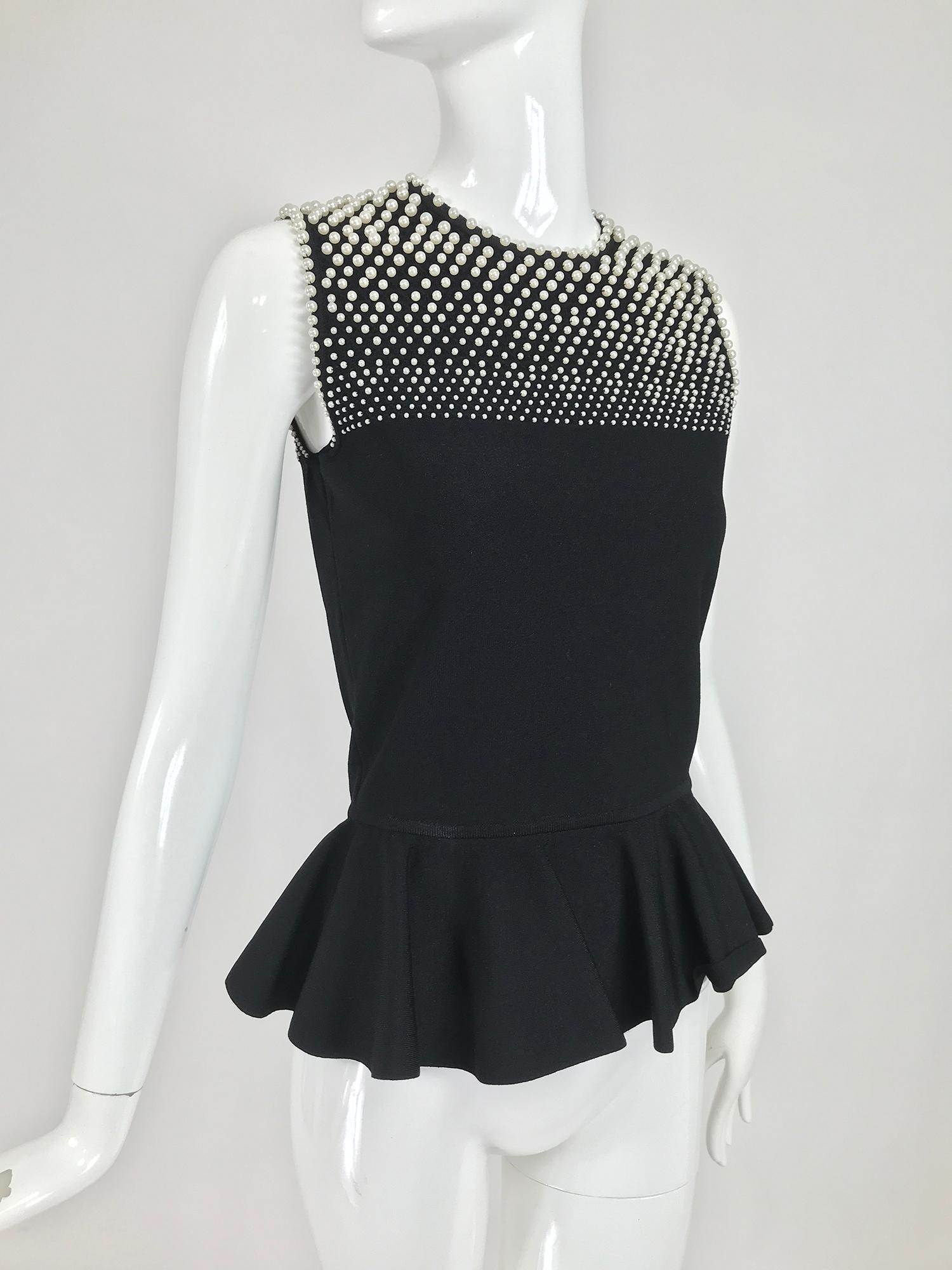 Alexander McQueen pearl bodice sleeveless peplum top in black stretch fabric. Jewel neckline closes at the back with a loop and button. The upper bodice front and back is covered with small, medium and large faux pearls. The top is fitted and