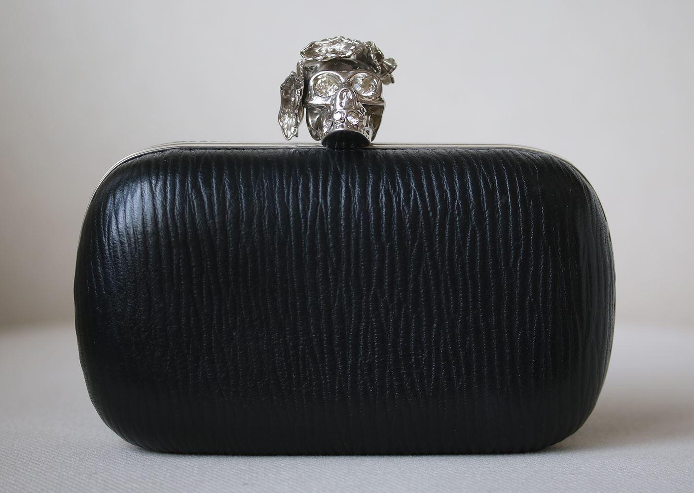Make a statement with this bold Alexander McQueen black textured leather poppy skull box clutch bag. Featuring box frame silhouette, this clutch is covered in gorgeous black grained leather. The clutch closes with a silver-tone metal and Poppy