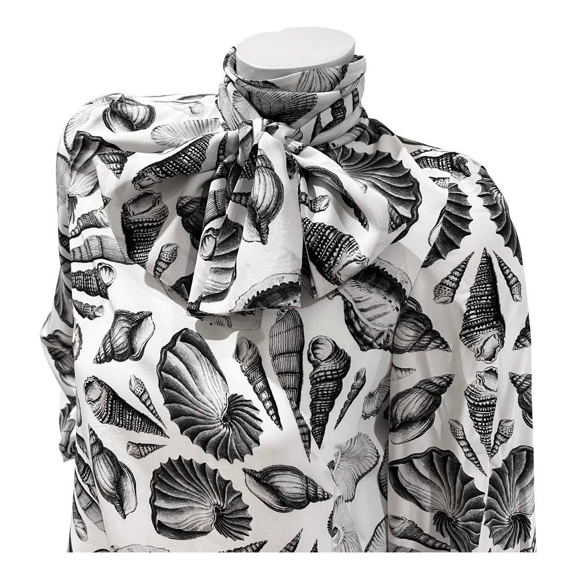 Vestito con stampa a conchiglia di Alexander McQueen 
Resort 2019 
Prodotto in Italia
Bianco con stampa di conchiglie nere 
Silhouette a turni
Maniche blouson 
Cravatta 
Chiusura dei polsini con un solo bottone 
Chiusura posteriore con doppio