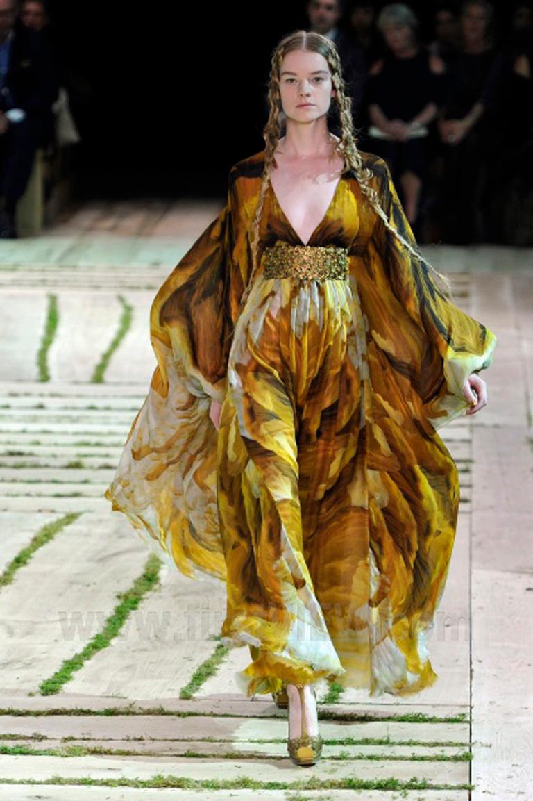 Robe de style caftan Alexander McQueen conçue par Sarah Burton lors de sa première collection s/s 2011 pour la marque.  Modèle Empire en mousseline de soie dans des tons chauds et sourds.  or  avec de grandes empreintes en forme de fond.  La bande