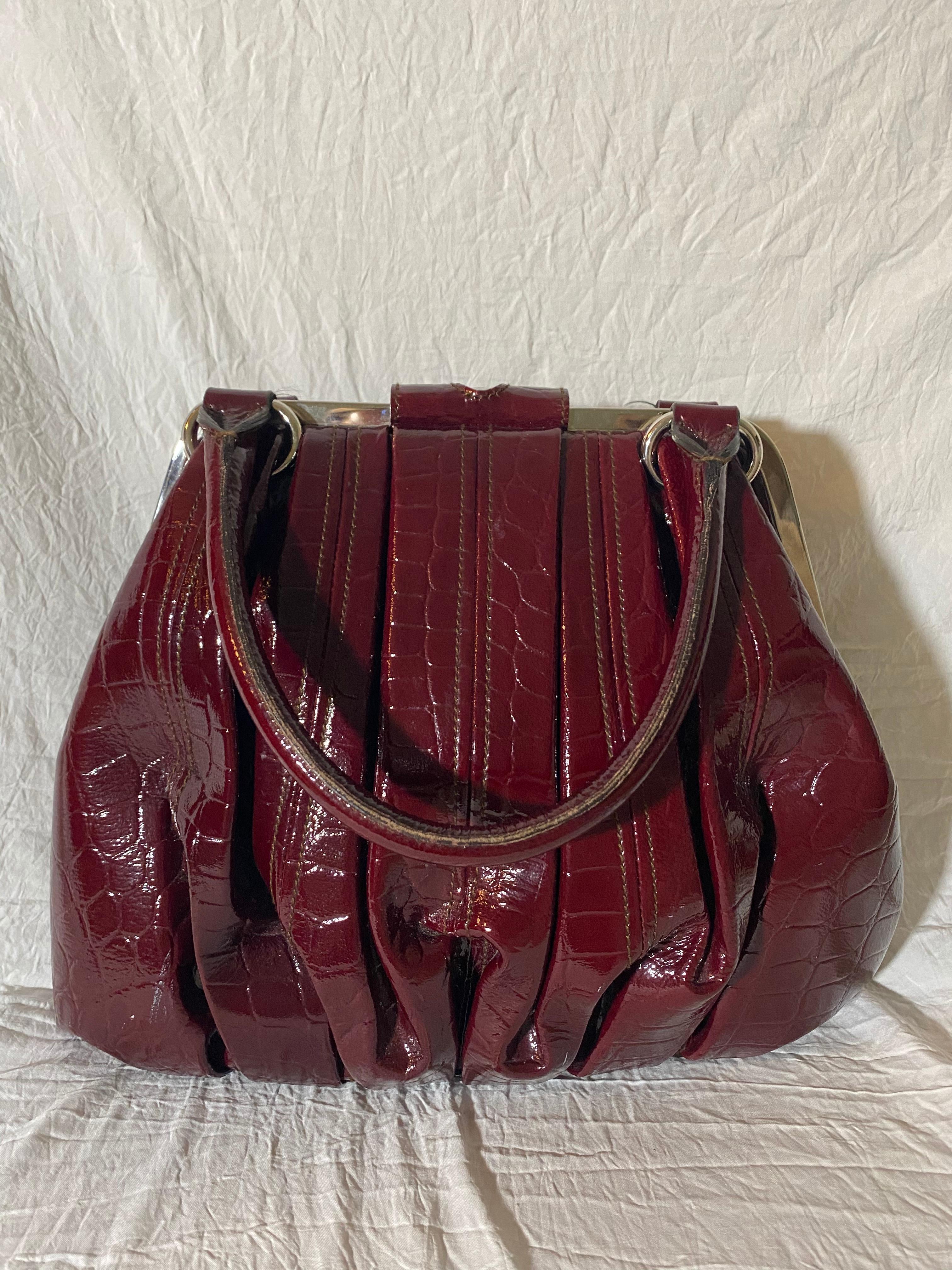Soft patent crocodile leather laid into structured pleats, silver-tone hardware and a fabric interior. 

Condition: Good used condition.
Exterior: Slight tarnishing and discoloration on hardware.
Interior: Lined with fabric, one interior pocket.