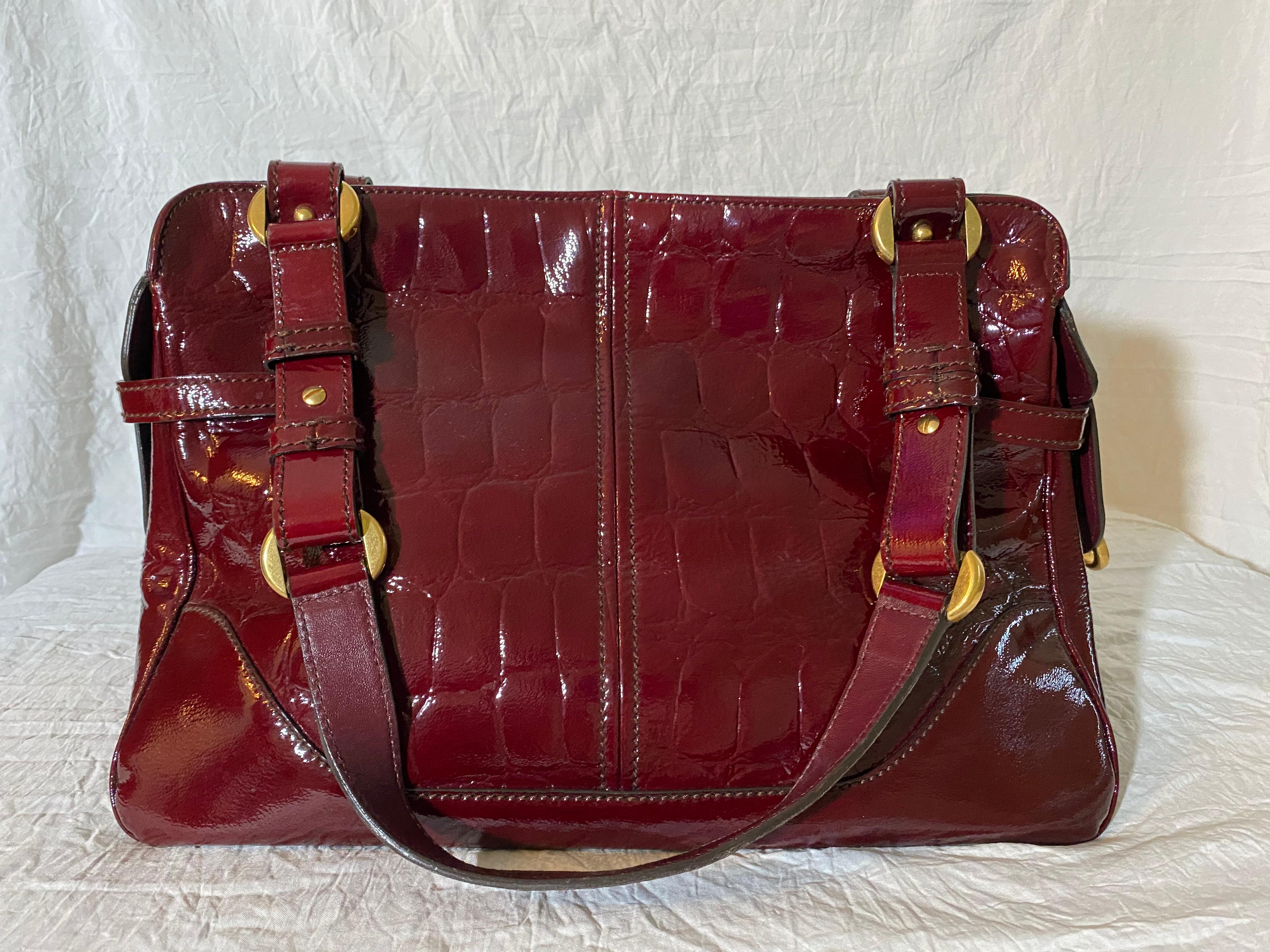 Patent crocodile leather, dusted gold-tone hardware and a fabric interior. 

Condition: Good used condition.
Exterior: Slight scuffing on hardware. 
Interior: Lined with fabric, one interior pocket.
Made In: Italy
Serial Number: 202659-204046
Dust