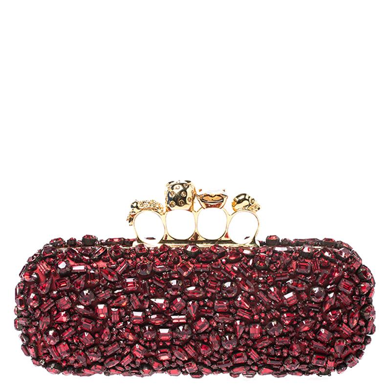 This knuckle box clutch from Alexander McQueen exudes versatility and luxury. Crafted from red leather, it features a boxy silhouette and is embellished with red crystals throughout. It comes with a well-sized suede-lined interior. This piece is