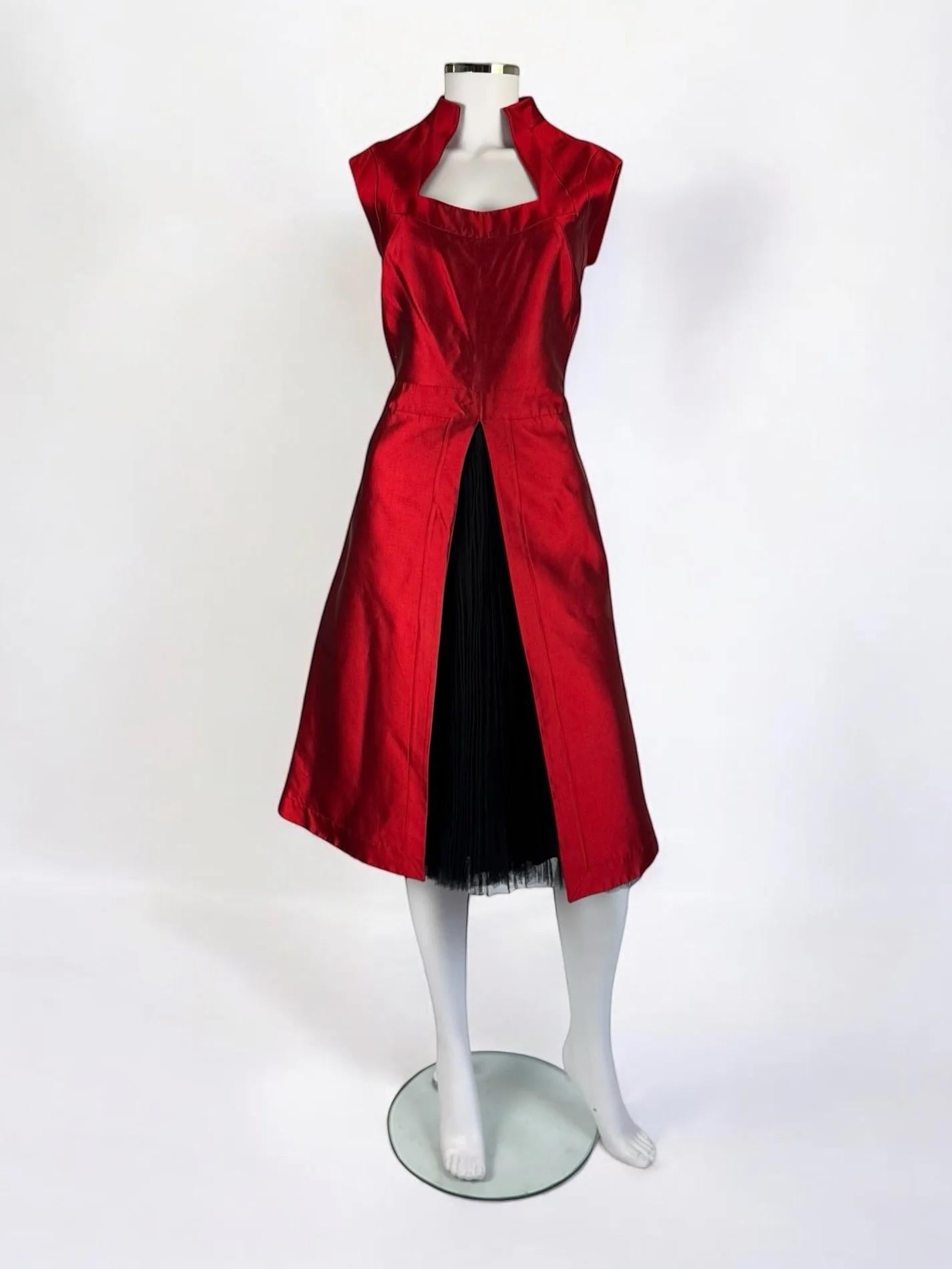 Alexander McQueen red mikado silk dress, 2007
Structured high collar, cap sleeves, and a squared neckline
A tailored bodice flows into an A-line skirt with a front slit, revealing a contrasting black pleated tulle skirt which is sewn into the