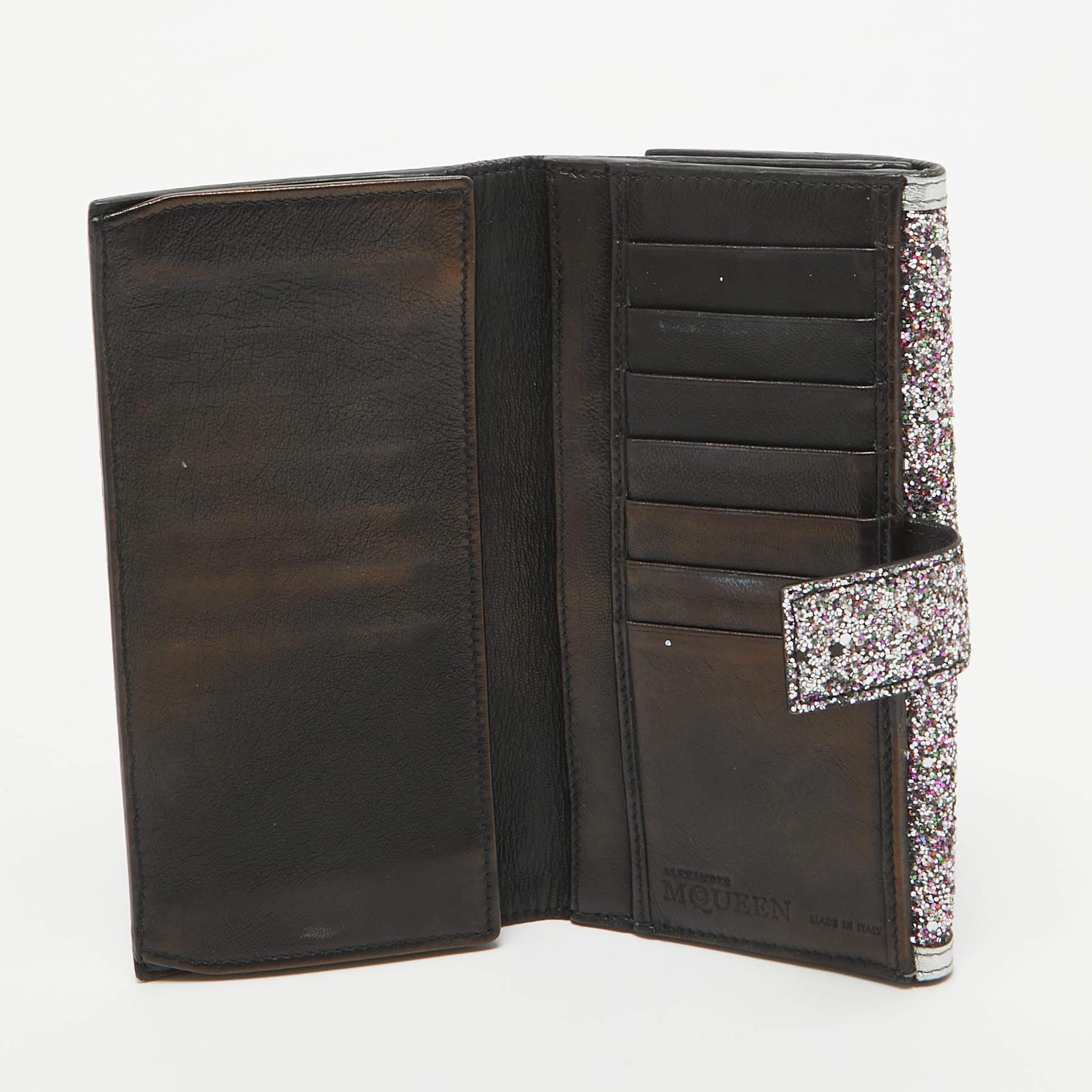 This Alexander McQueen continental wallet is a luxurious accessory for everyday use. It has a pretty glitter and leather exterior and a well organized interior.