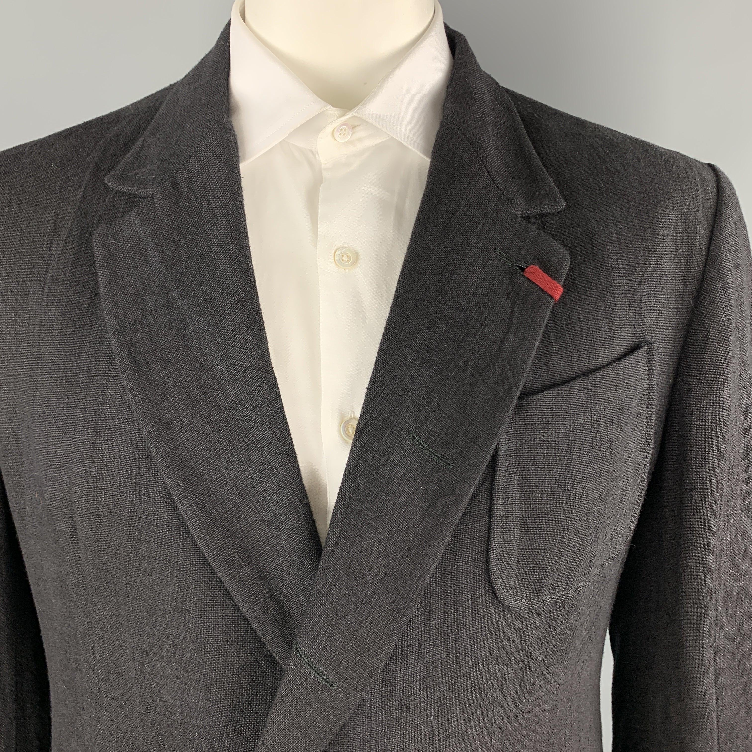 Le manteau de sport ALEXANDER MCQUEEN est réalisé en lin noir texturé et présente un revers à encoche avec patte de boutonnage rouge, un simple boutonnage, deux boutons cachés sur le devant, et une patte de boutonnage à l'avant. 
poignets à boutons