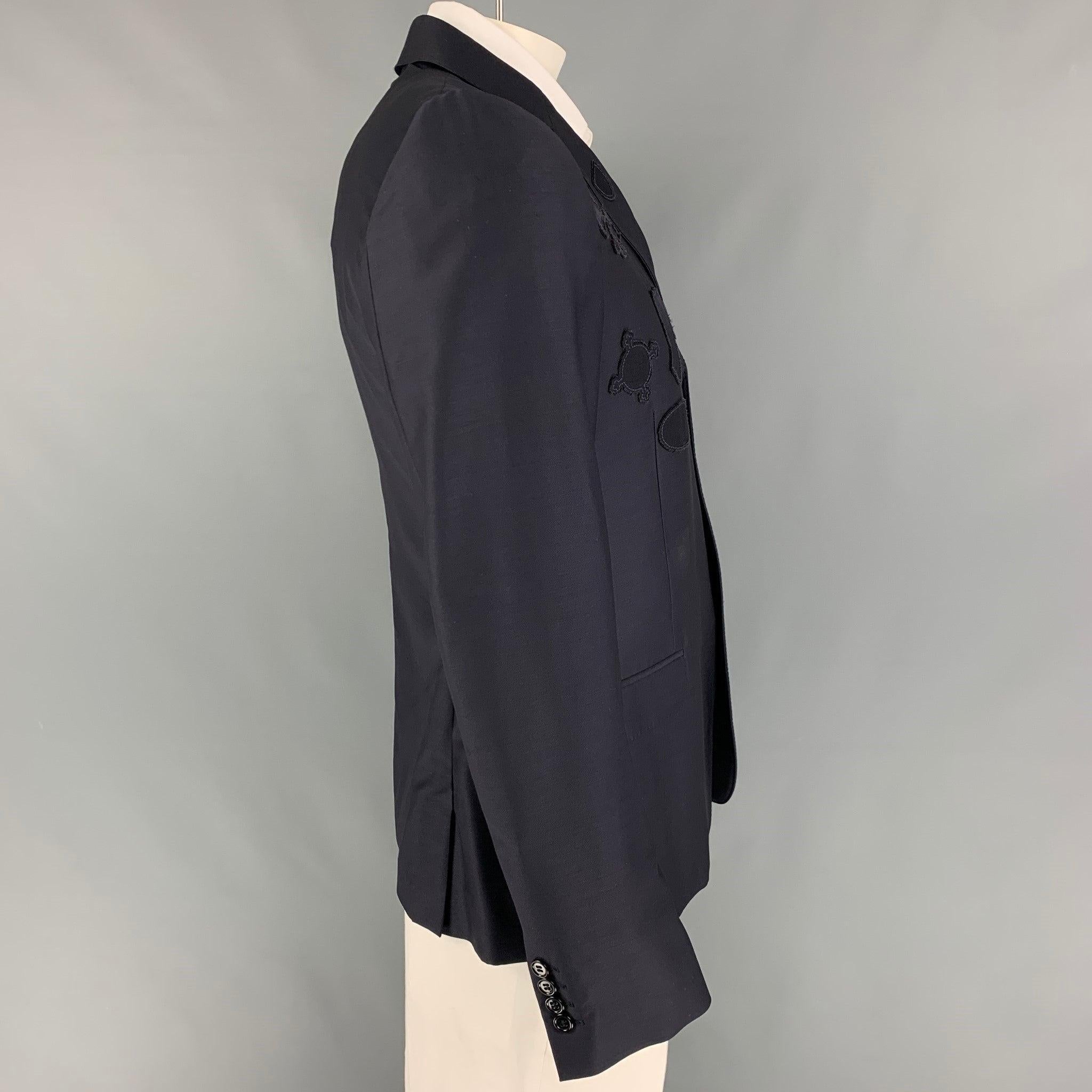 ALEXANDER McQUEEN sport coat comes in a navy wool with a half liner featuring a notch lapel, patch designs, flap pockets, double back vent, and a three button closure. Made in Italy. Excellent
Pre-Owned Condition. 

Marked:   54 

Measurements: 

