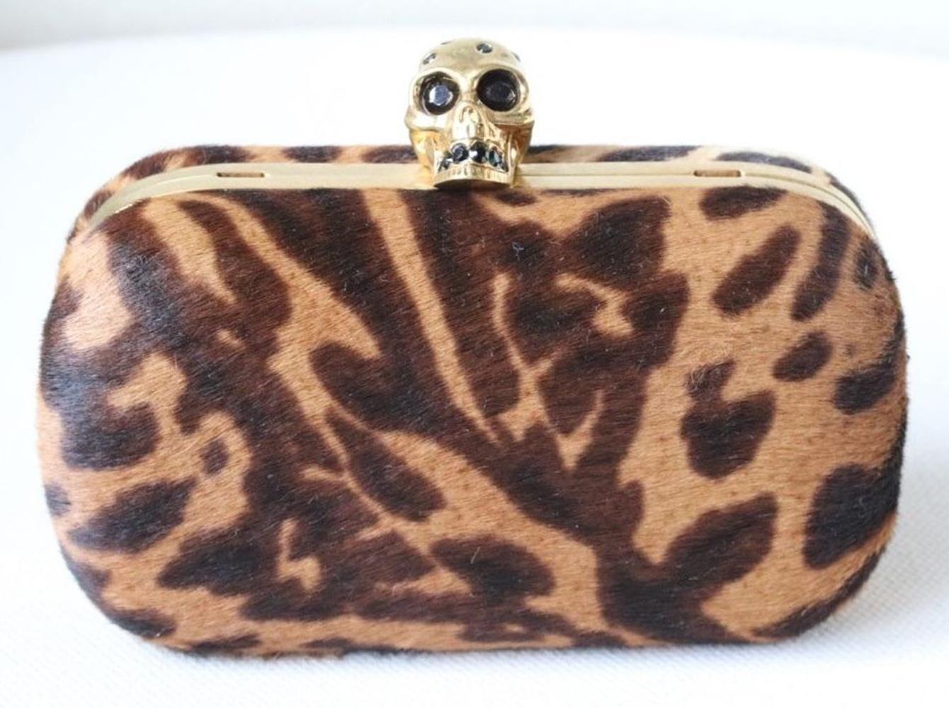 The combination of opulent ocelot print and a Swarovski crystal-encrusted skull makes Alexander McQueen's compact box clutch a darkly decadent accessory. Ocelot-print calf hair. Detachable buckle-fastening shoulder strap. Gold brass frame. Fully