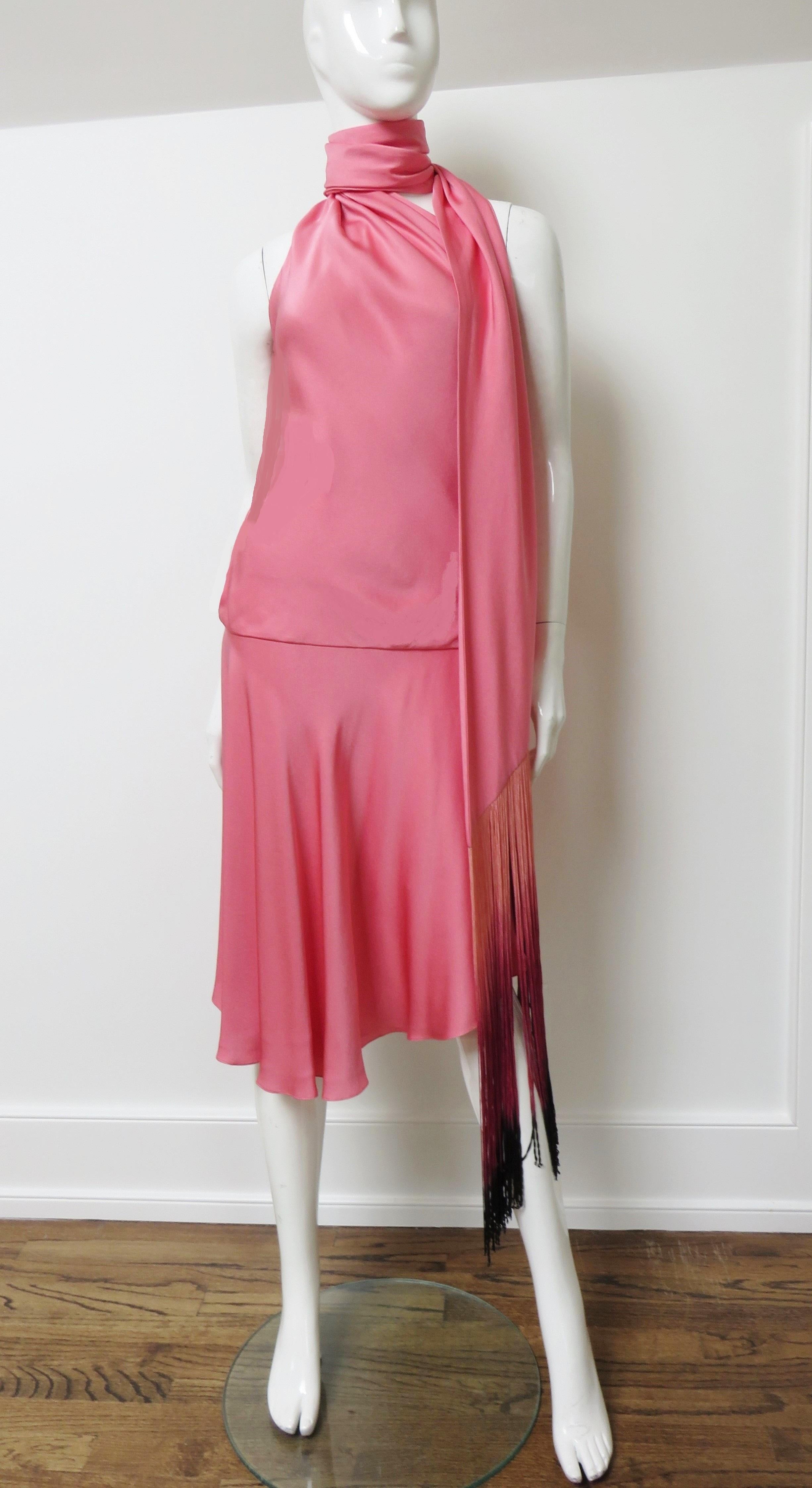 A gorgeous pink silk dress from Alexander McQueen. The dress's halter neckline is created with a silk fringe trimmed long scarf which wraps and drapes around the neck in a number of configurations.  It is lined in pink silk, has a side zipper and is