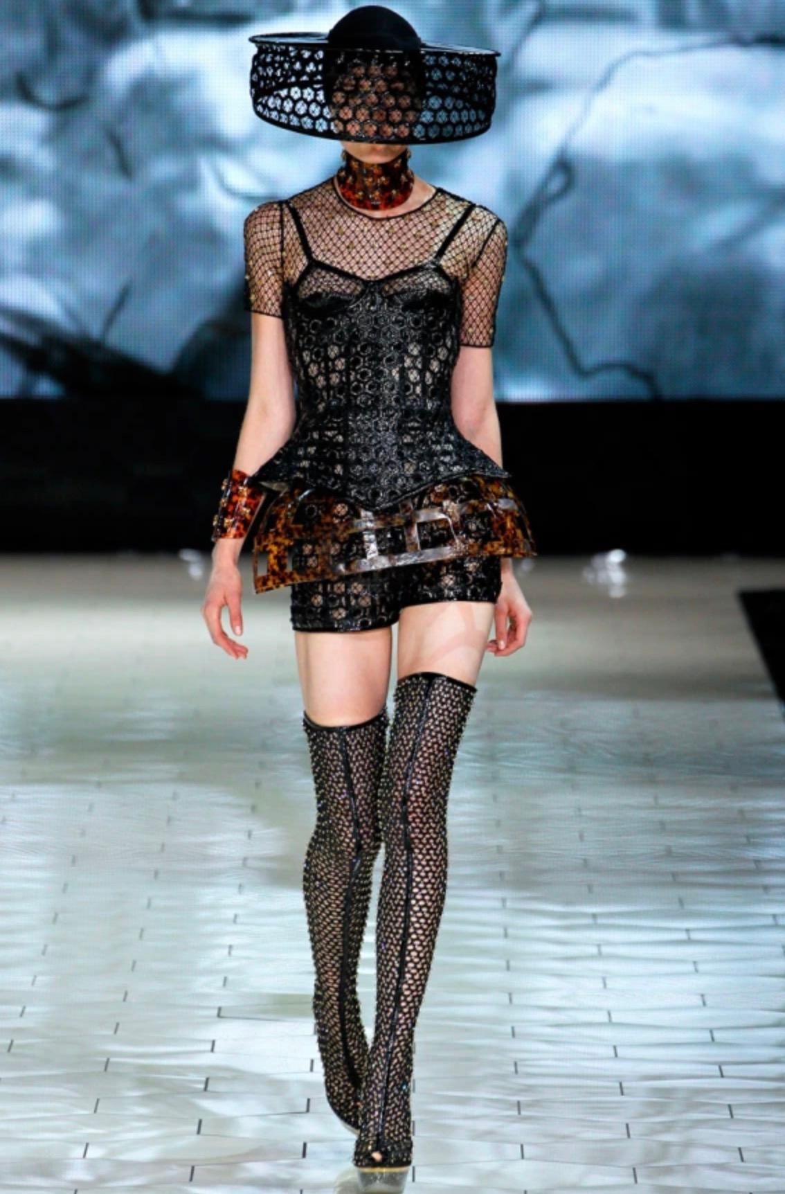 The Alexander McQueen Spring/Summer 2013 Black Honeycomb Corset is a striking testament to the brand's iconic interplay between structured silhouettes and avant-garde aesthetics. 
Extremely rare gorgeous silk and black patent leather bustier,