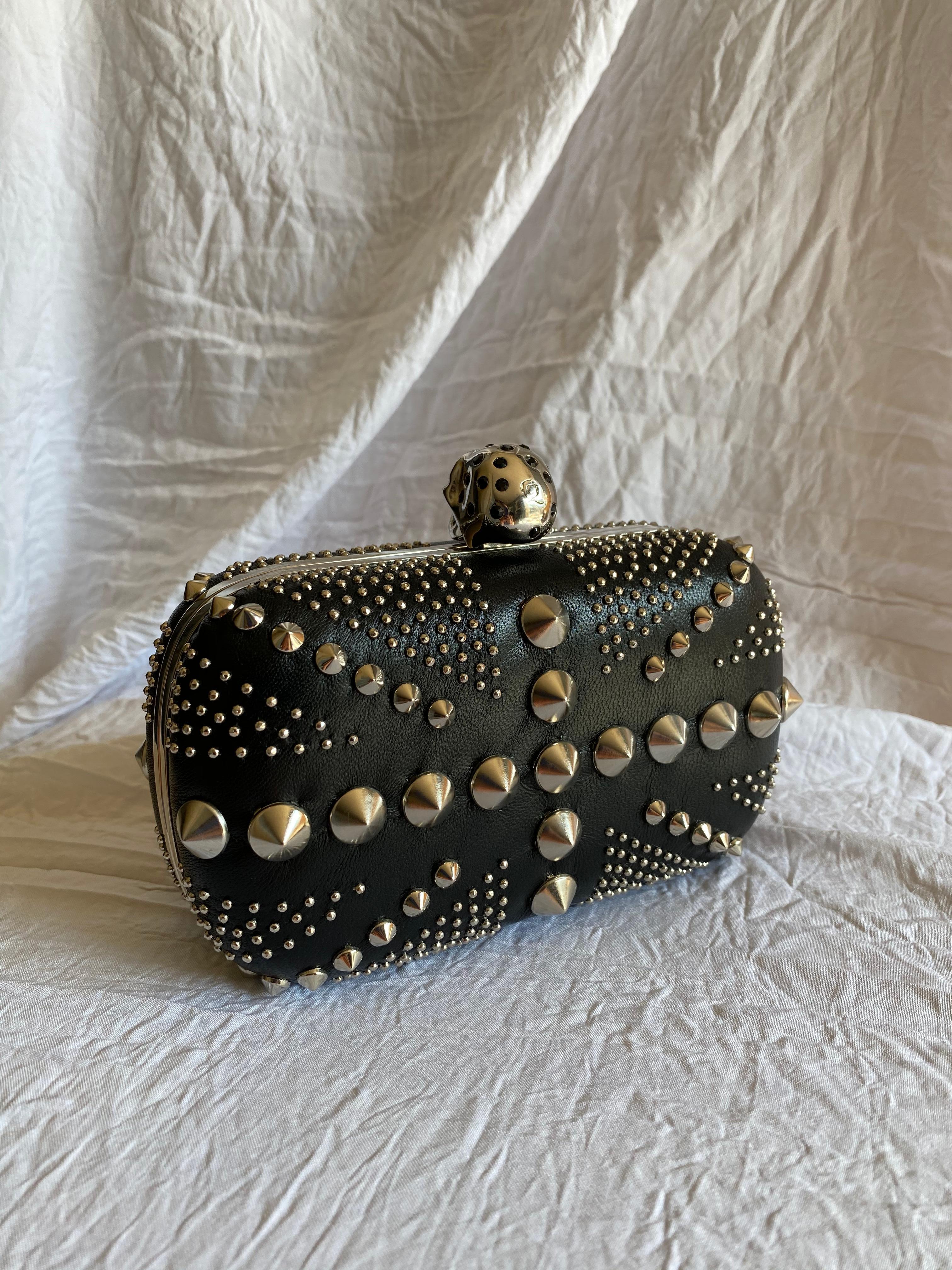 Campy UK patriotism intersects with relentless grunge in this McQueen classic. Made with smooth full grain leather, silver-tone hardware, and black Swarovski crystal eyes.

$1,200.00

Condition: Like new, never used. 
Exterior: All studs and stones