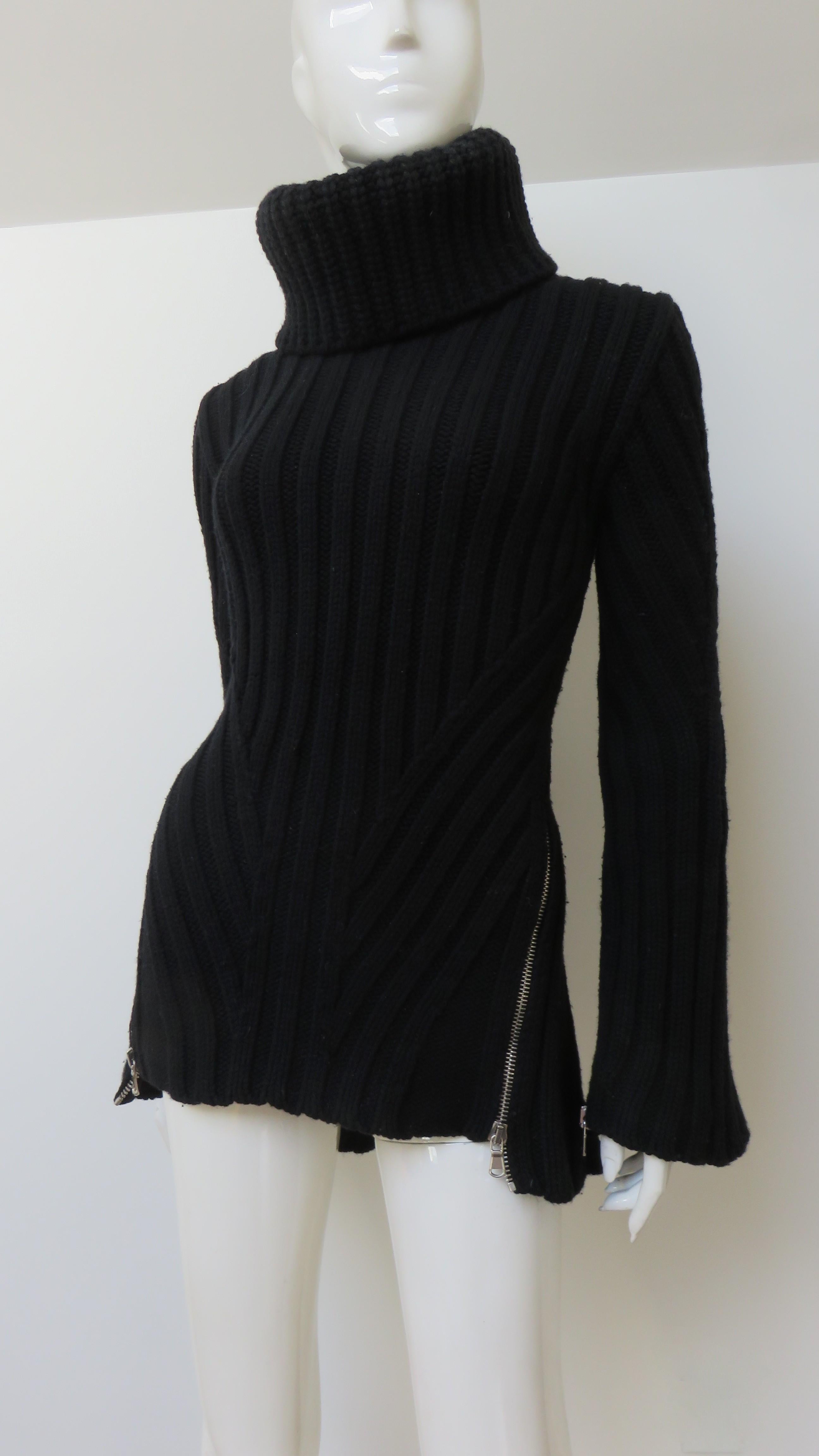 A fabulous black wool cashmere blend sweater from Alexander Mcqueen.  It is a semi fitted turtleneck with long, subtle flaired sleeves with zippers along their length and a flattering ribbed pattern at the waist front and back.  The sweater is