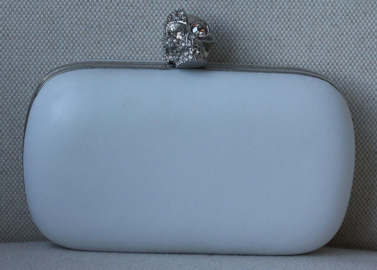 Two faced skull clutch in optic white from alexander mcqueen. This heavy distressed leather box clutch features silver-toned hardware, and a push lock skull closure with etched and faceted crystal details.

Dimensions: Approx. 14 x 9 x 5 cm