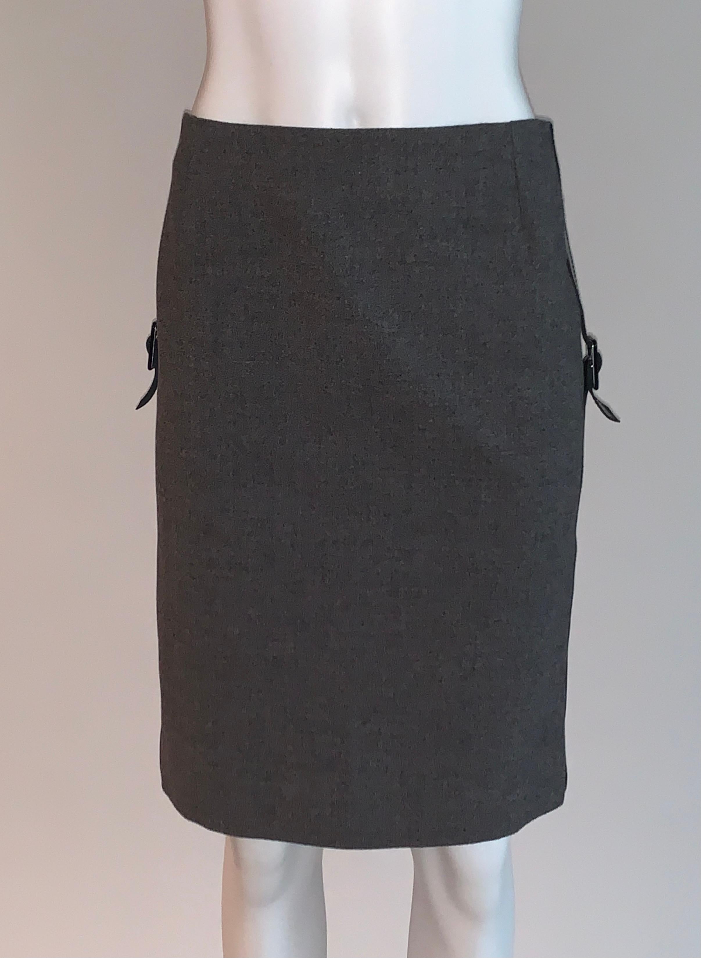 Alexander McQueen grey pencil skirt with black patent leather accent strips at side that fasten just below hip with a patent buckle. Back zip and hook and eye.

96% virgin wool, 4% leather.
Fully lined in 57% viscose, 43% polyester.

Made in