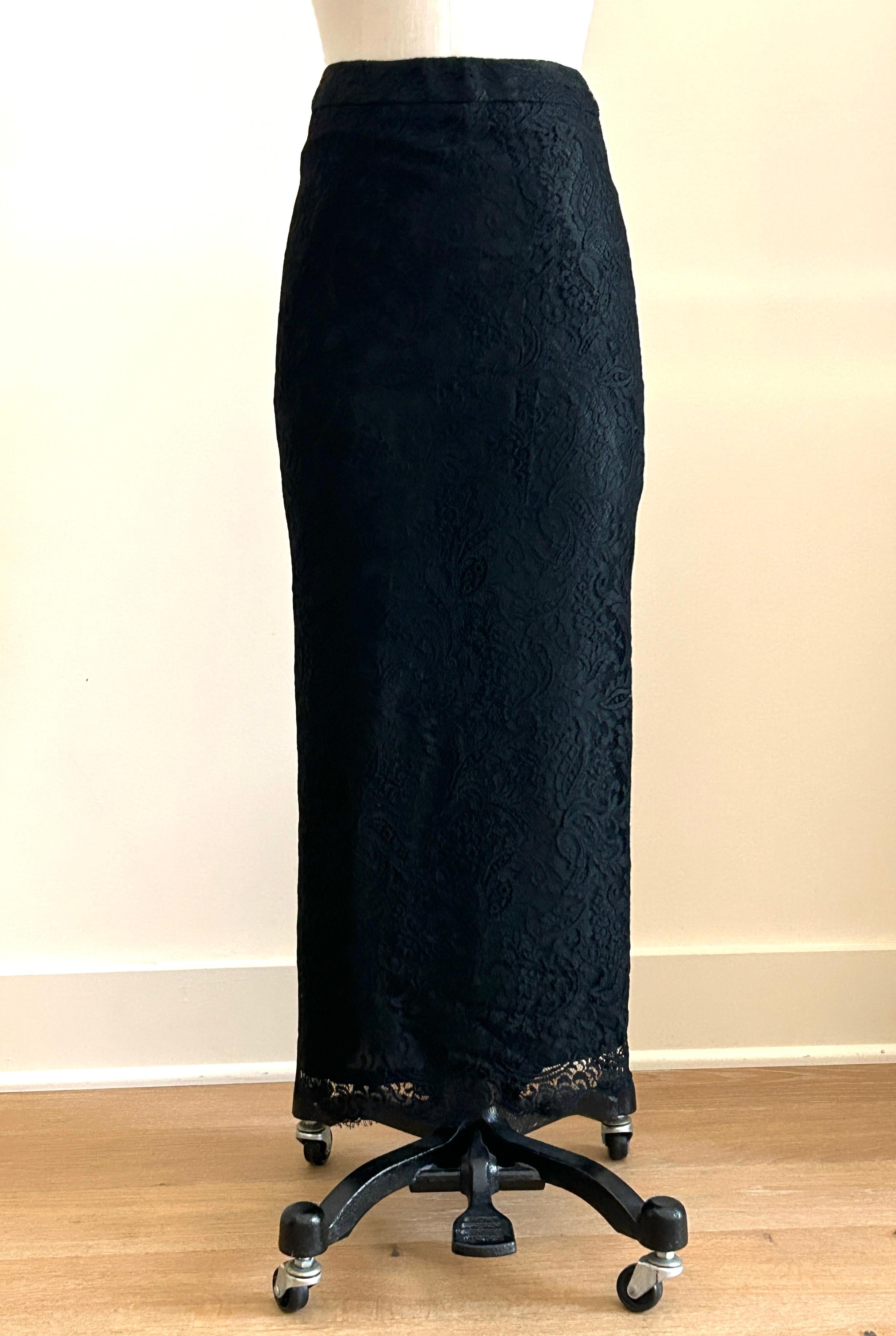 Longue jupe en dentelle florale noire d'Alexander McQueen avec une légère traîne dans le dos, circa 1990 ou début 2000. Étonnamment ajusté avec un ourlet festonné. Fermeture à glissière et bouton au dos. 

La taille de ce modèle varie de midi à maxi