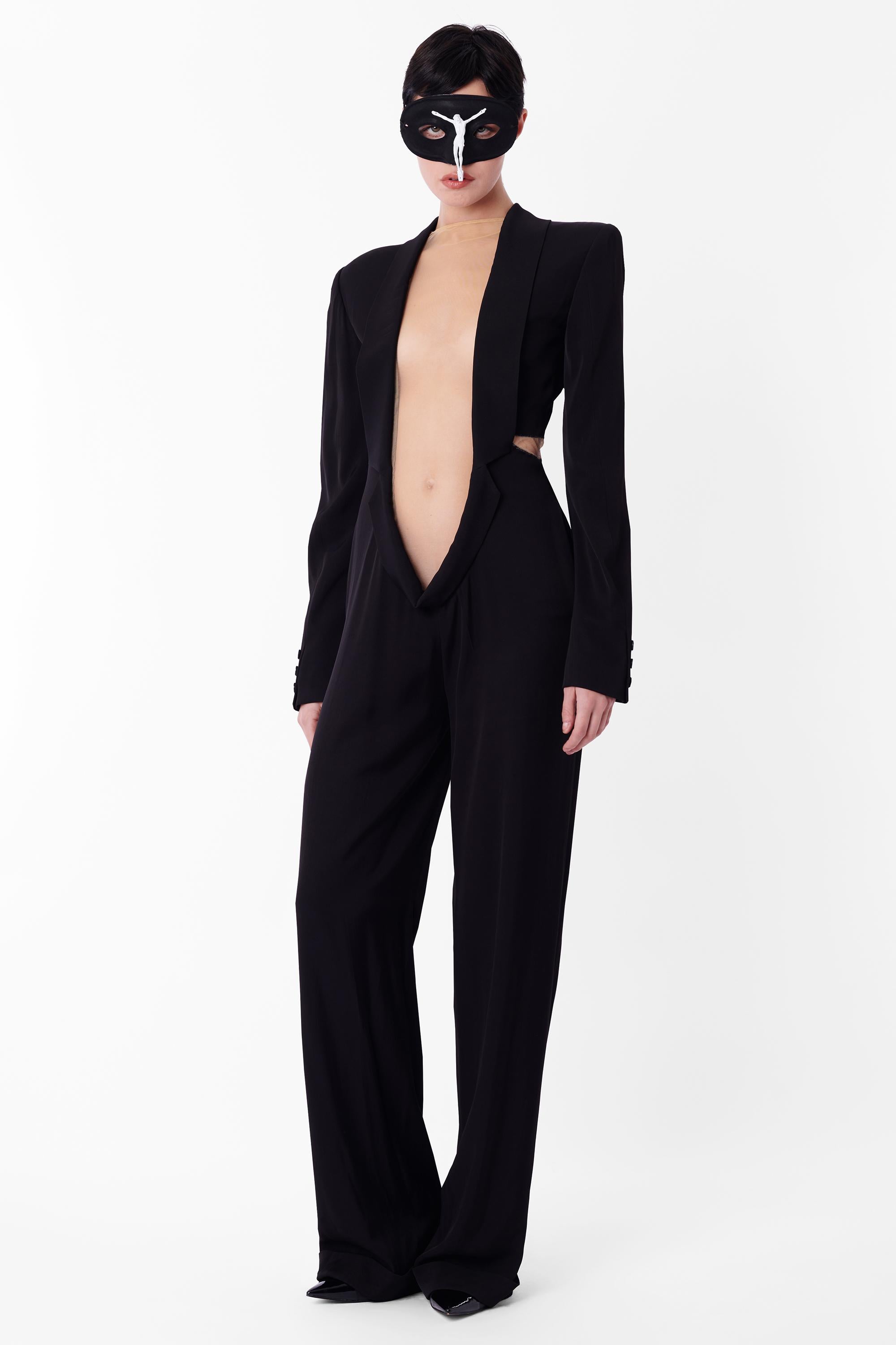 Vintage Alexander McQueen Spring Summer 1997 black jumpsuit, look 22 from the ‘La Poupée’ collection. Features black long-sleeve silhouette with structured upper with shoulder pads, lapel running through to the lower abdomen, sheer centre covering