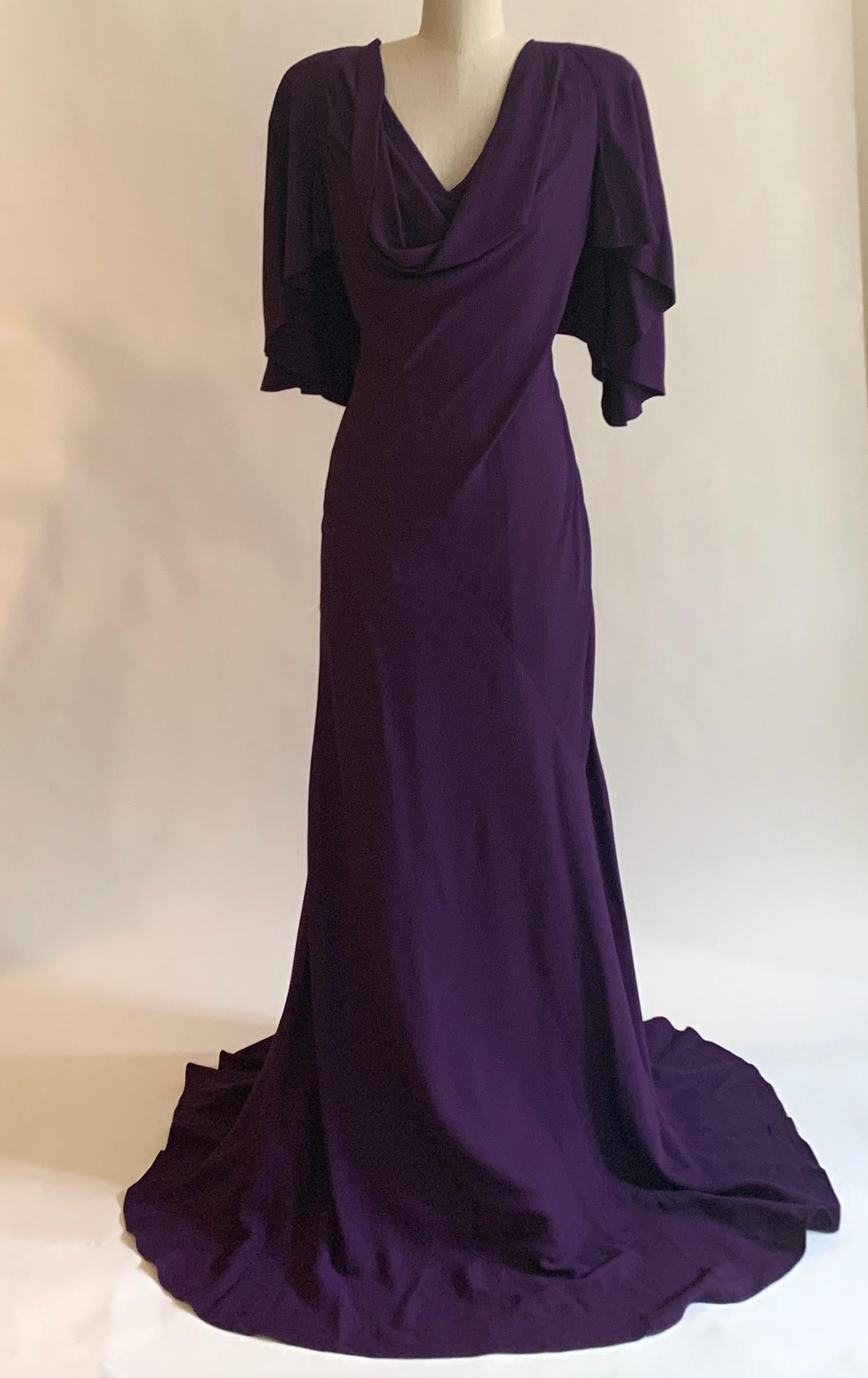 Alexander McQueen 2010 violet purple gown with a short draped sleeve that opens into a cape back. Bias seam at skirt opens the gown's shape from a fitted hip to a swishy bottom. Padded at shoulders. Hidden back and side zip create a super tailored