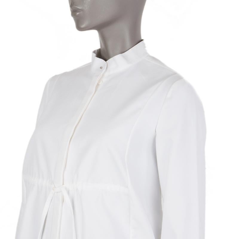 Alexander McQueen long shirt in off-white cotton (98%) and elastane (2%). With band collar, cinched elastic waist with drawstring, straight yoke, and stud-buttoned cuffs. Closes with one stud and concealed buttons on the front. Has been worn and is