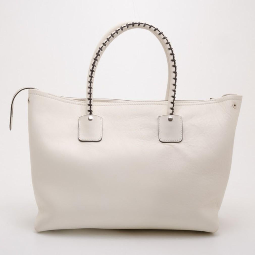 This Alexander McQueen White Folkstitch tote is just what every city girl needs. Crafted from crisp white leather, it is beautifully detailed with brown stitching, a front zip pocket, tassels, leather ID tag and rolled leather handles. The interior