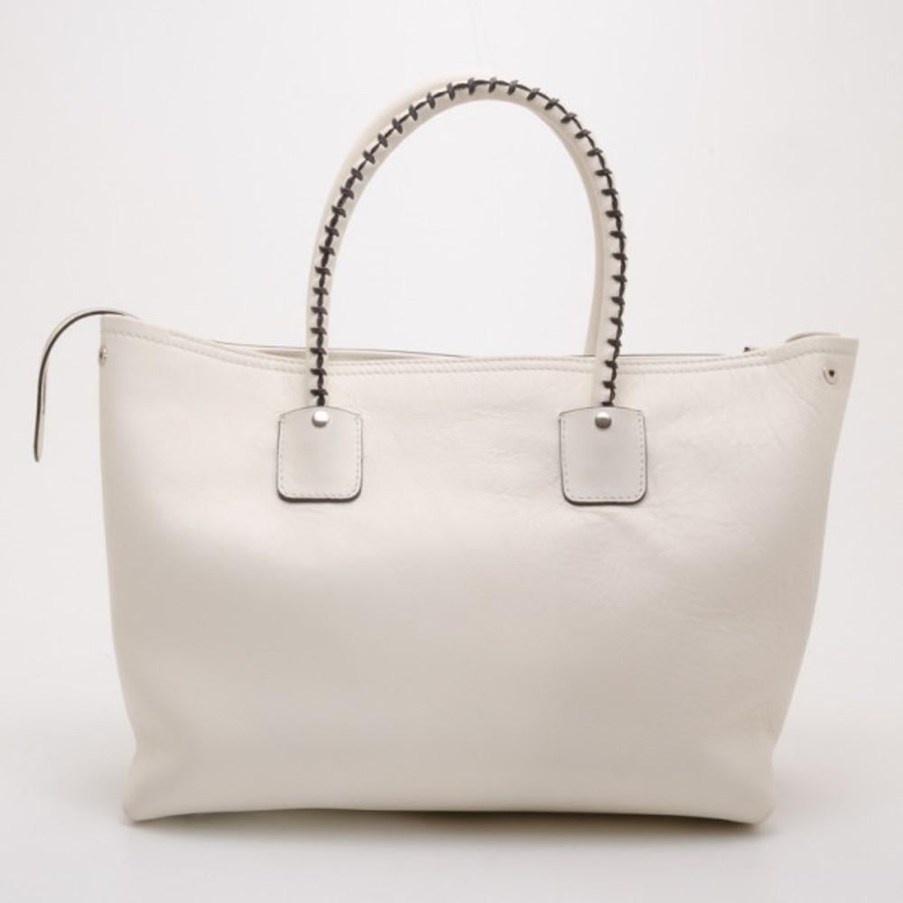 This Alexander McQueen White Folkstitch tote is just what every city girl needs. Crafted from crisp white leather, it is beautifully detailed with brown stitching, a front zip pocket, tassels, leather ID tag and rolled leather handles. The interior