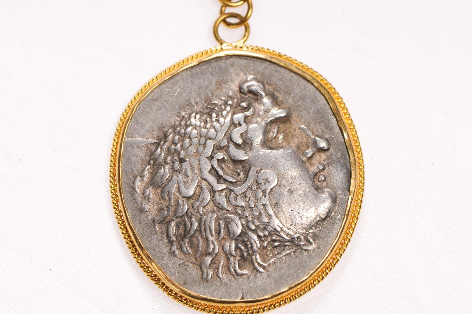 An Authentic Greek (Macedonian) Alexander the Great Tetradrachm Coin, 336 - 323 BC, set in a 22k Gold Bezel and Bail with an Emerald Stone Accent. Obverse of Coin is Heracles and Zeus Reverse. Coin pendant measures approximately 2 1/3