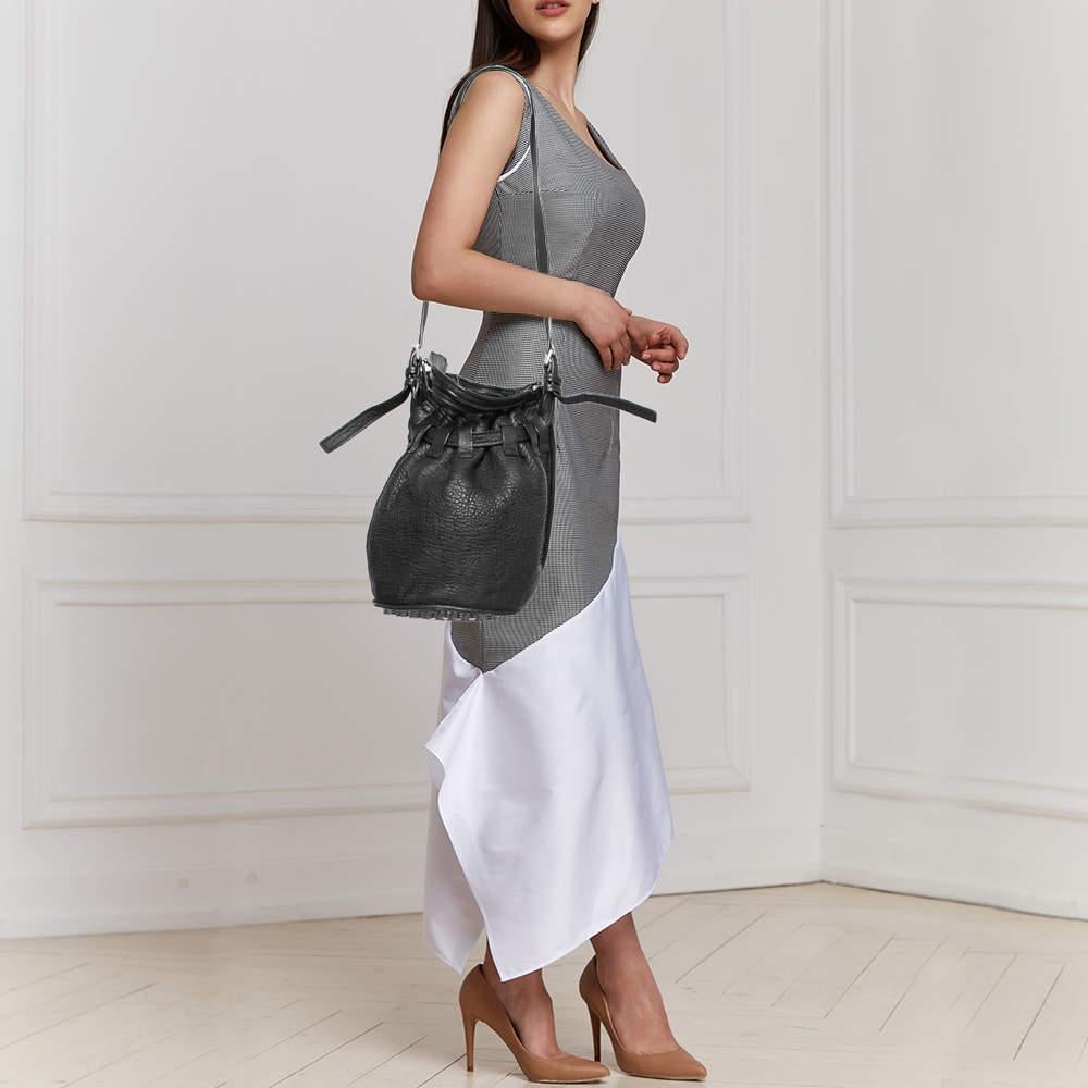 Lleva tus objetos de uso diario de forma elegante con este bolso cubo Diego de Alexander Wang. Se ha diseñado con piel negra texturizada y se ha realzado con apliques plateados. El detalle del cordón revela un interior forrado de nailon, que puede