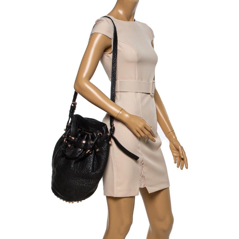 This chic Diego bucket bag from Alexander Wang offers ample style and reliability. Crafted from black leather, the bag features a single top handle, an adjustable shoulder strap, and protective metal feet at the bottom. The drawstring closure opens