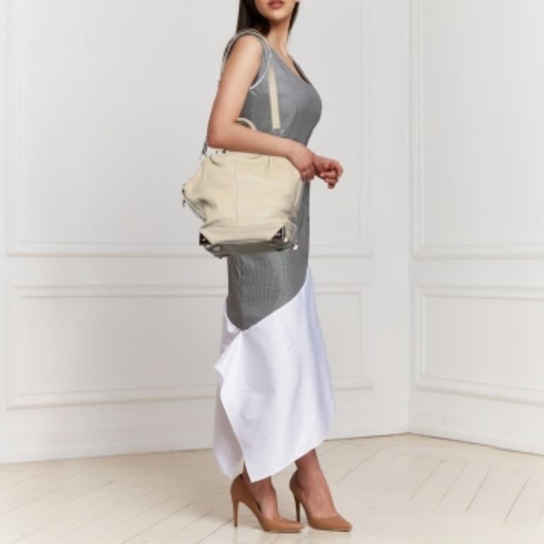 Bien estructurada y con mucho estilo, esta cartera de Alexander Wang merece ser tuya. Se ha confeccionado en piel de color crema y está diseñado con dos asas y una correa para el hombro. El interior de tela tiene espacio suficiente para guardar tus