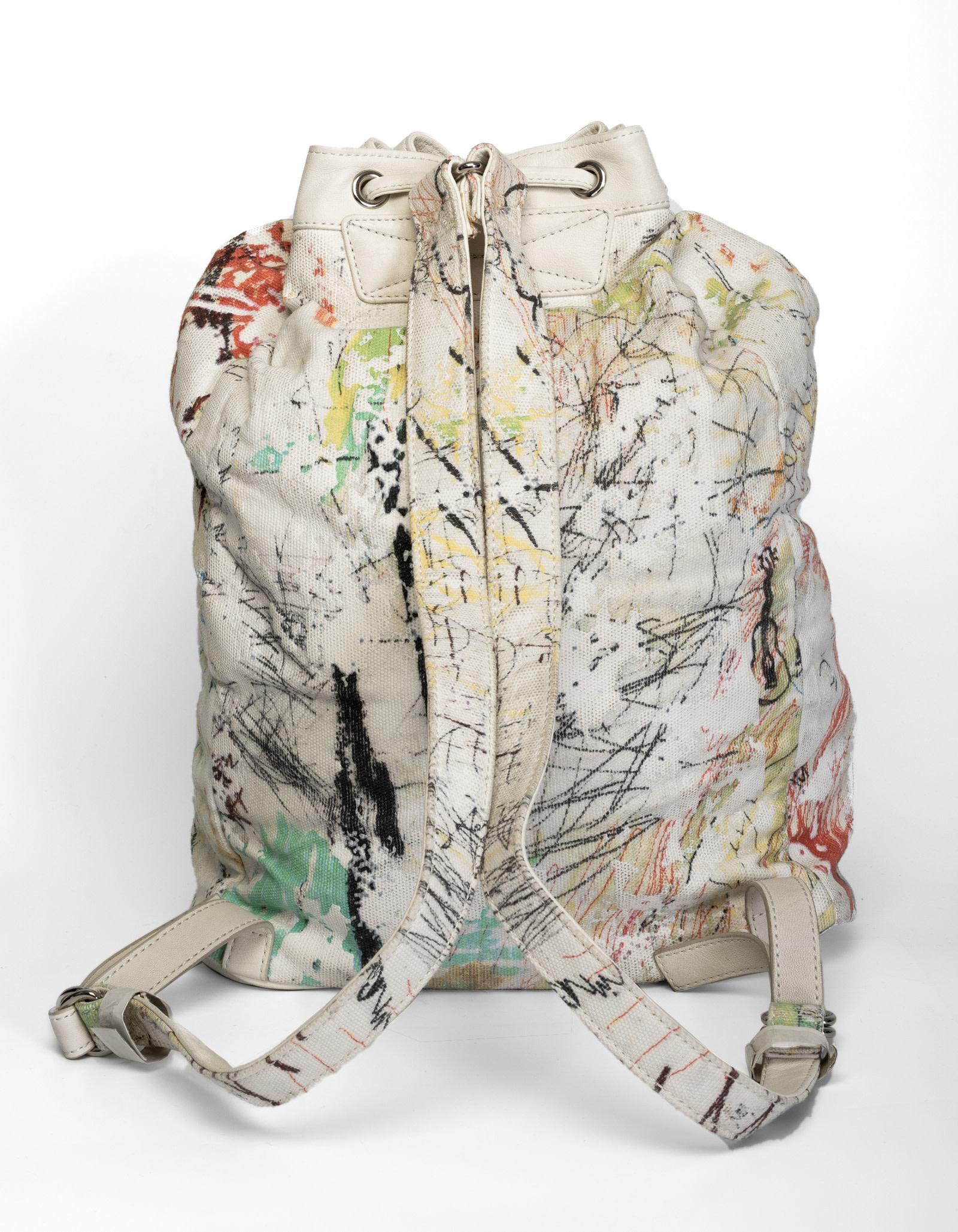 Dieser Rucksack von Alexander Wang hat eine Außenseite aus weißem Canvas mit Graffiti-Druck, einen Kordelzugverschluss, silberfarbene Hardware, eine Innentasche mit Reißverschluss und ein Innenfutter aus gewebtem schwarzem Stoff.

FARBE: