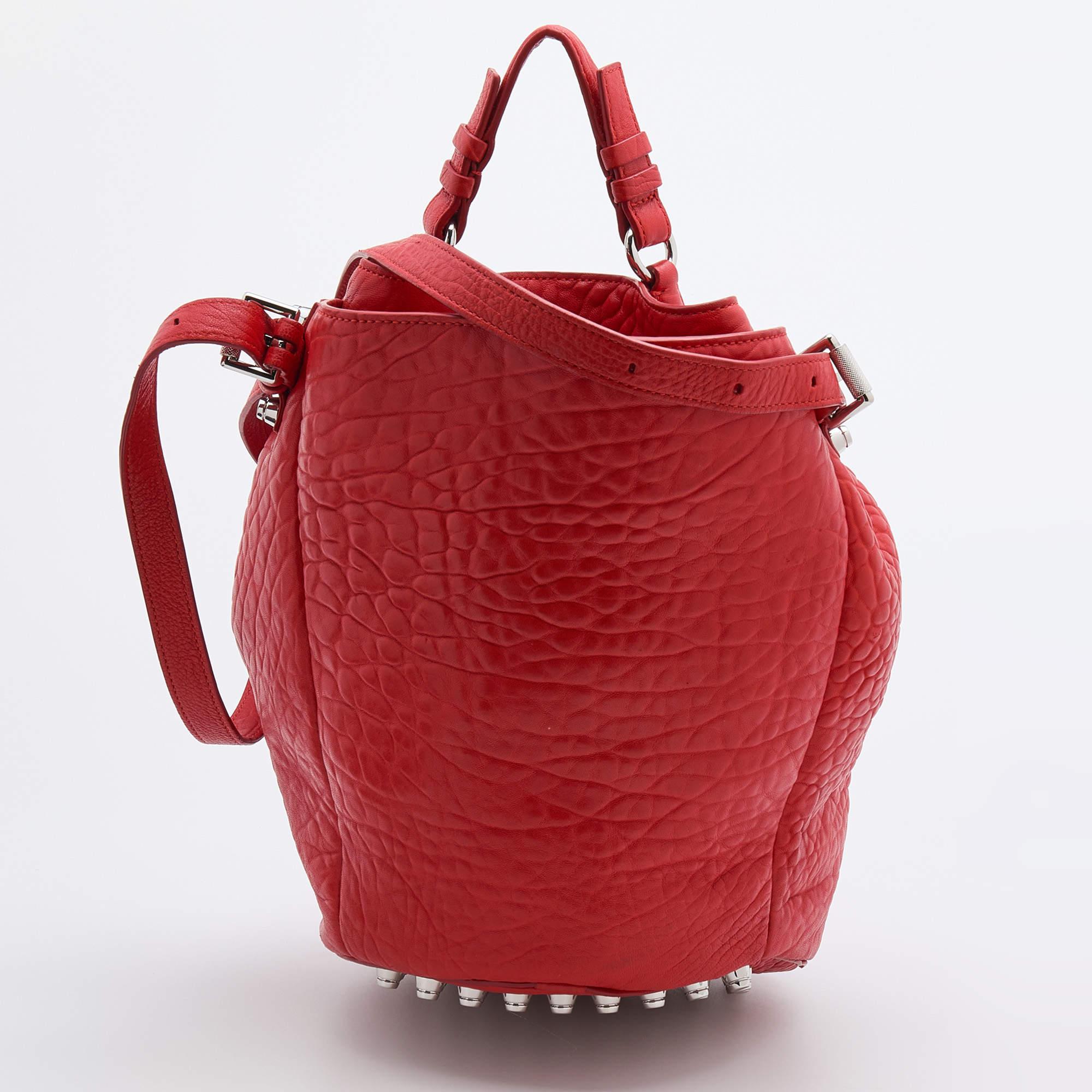 This chic Diego bucket bag from Alexander Wang offers ample style and functional ease. Crafted from textured leather, the bag features a single top handle, an adjustable shoulder strap, and silver-tone studs. The drawstring closure opens to a nylon