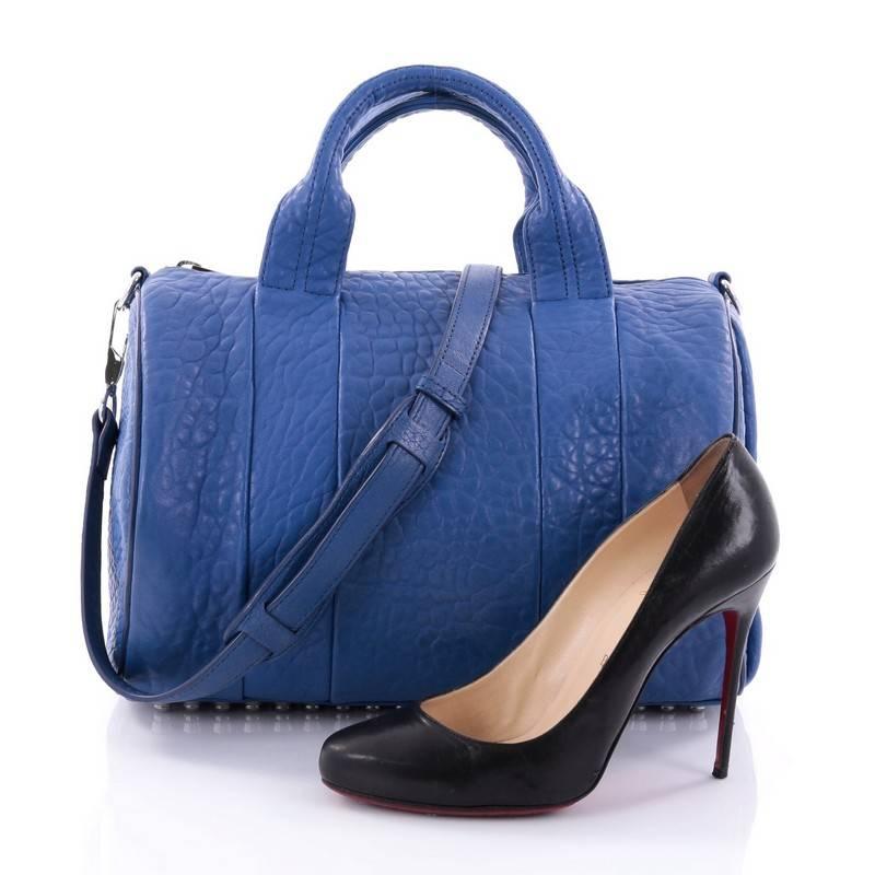 This authentic Alexander Wang Rocco Satchel Leather is fashion-forward, tasteful and makes a bold statement. Crafted from blue leather, this edgy duffle bag features dual flat leather handles, signature base studs detail and silver-tone hardware
