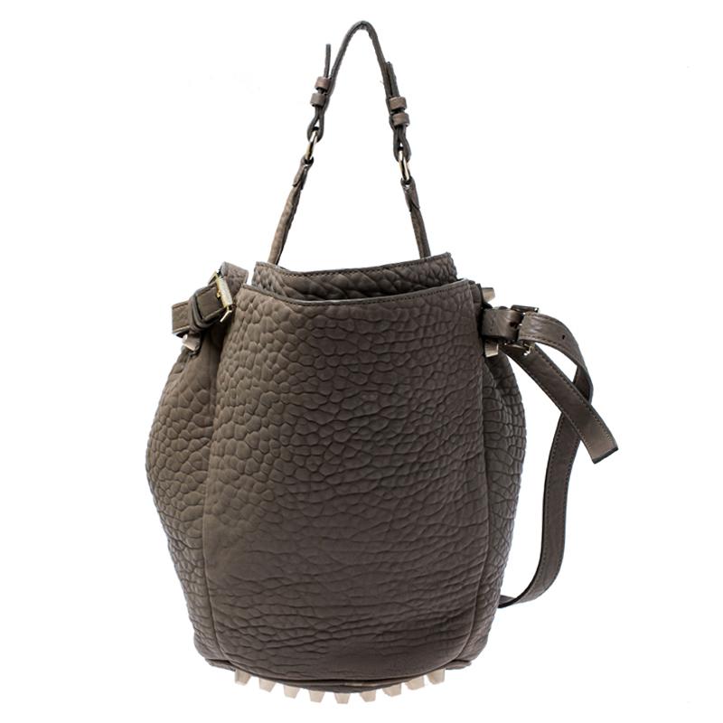 This chic Diego bucket bag from Alexander Wang is not only a symbol of style but also reliability. Crafted from taupe textured leather, the bag features a single top handle, an adjustable shoulder strap and protective metal feet at the bottom. The