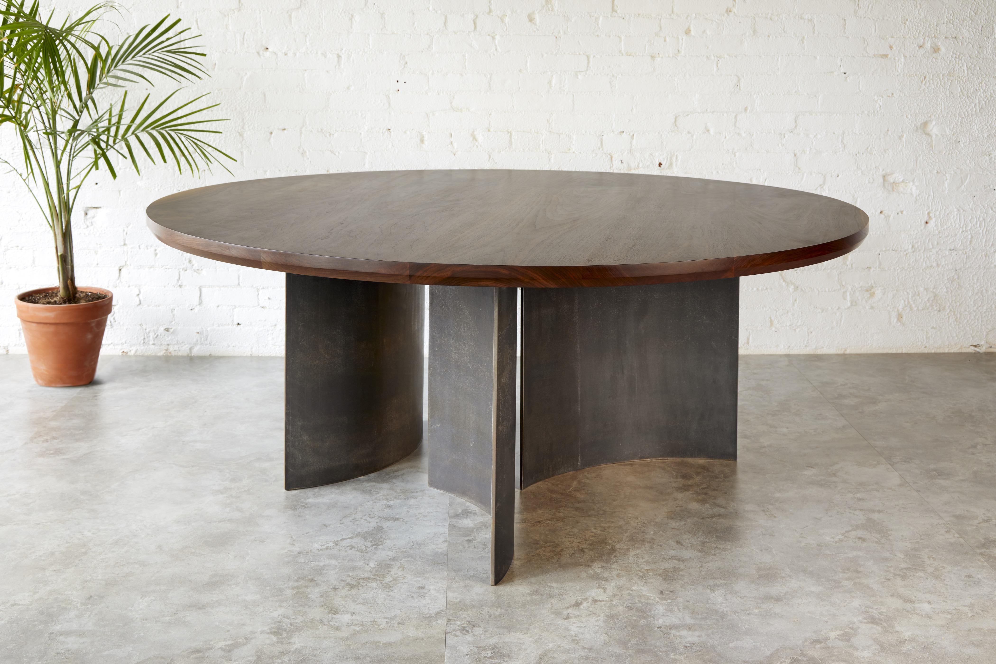 The Ban Round Table is a contemporary dining table that merges sculptural steel with the natural beauty of solid wood. Designed by award-winning designer Kirk Van Ludwig, this piece reinterprets the original Ban Rectangle Table, first created in