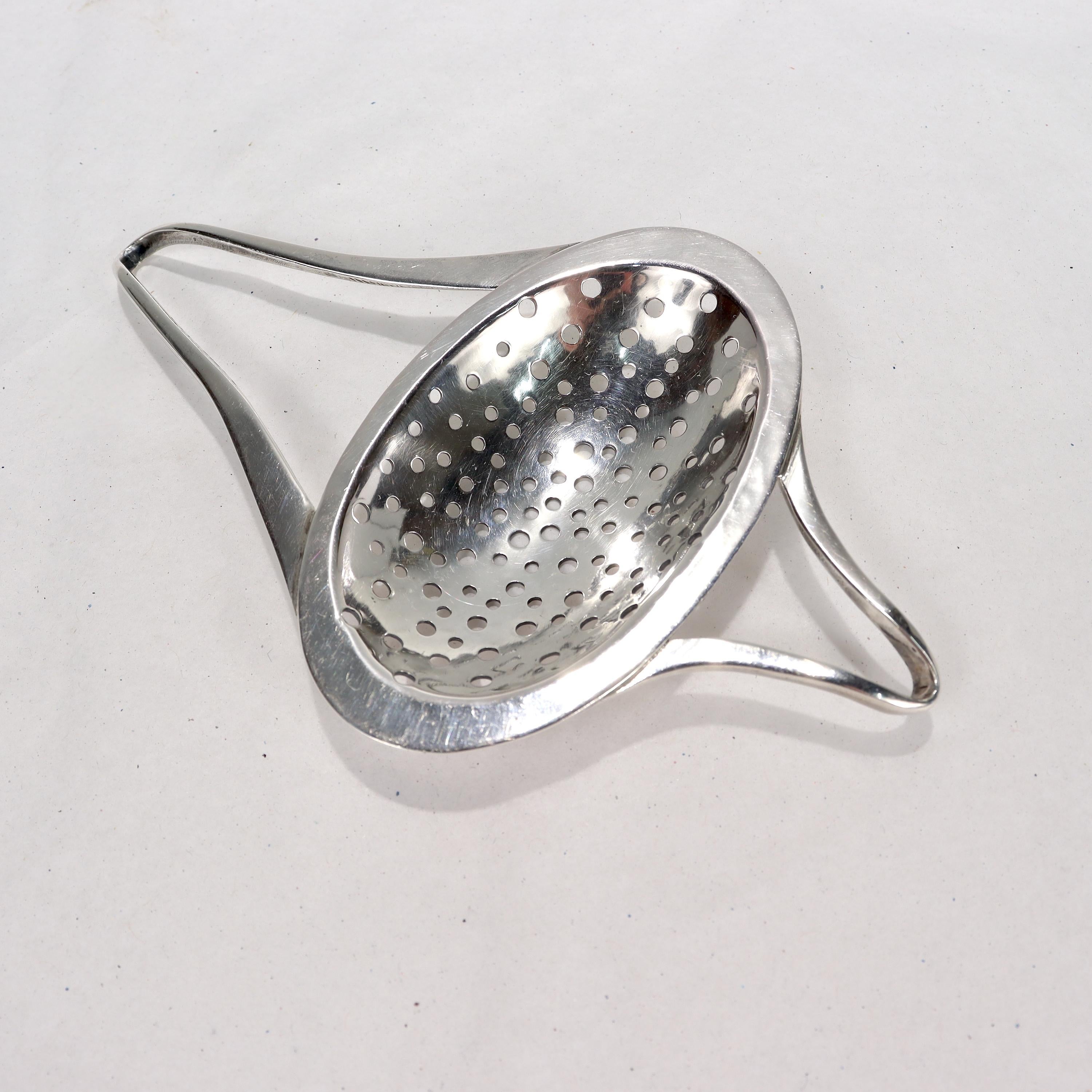 Offered here for your consideration is, A fine Mid-Century Modern hand-crafted tea strainer.

In sterling silver.

By Alexandra Solowij Watkins. Solowij Watkins is a renowned Polish-American female silversmith. After training in Montreal she was