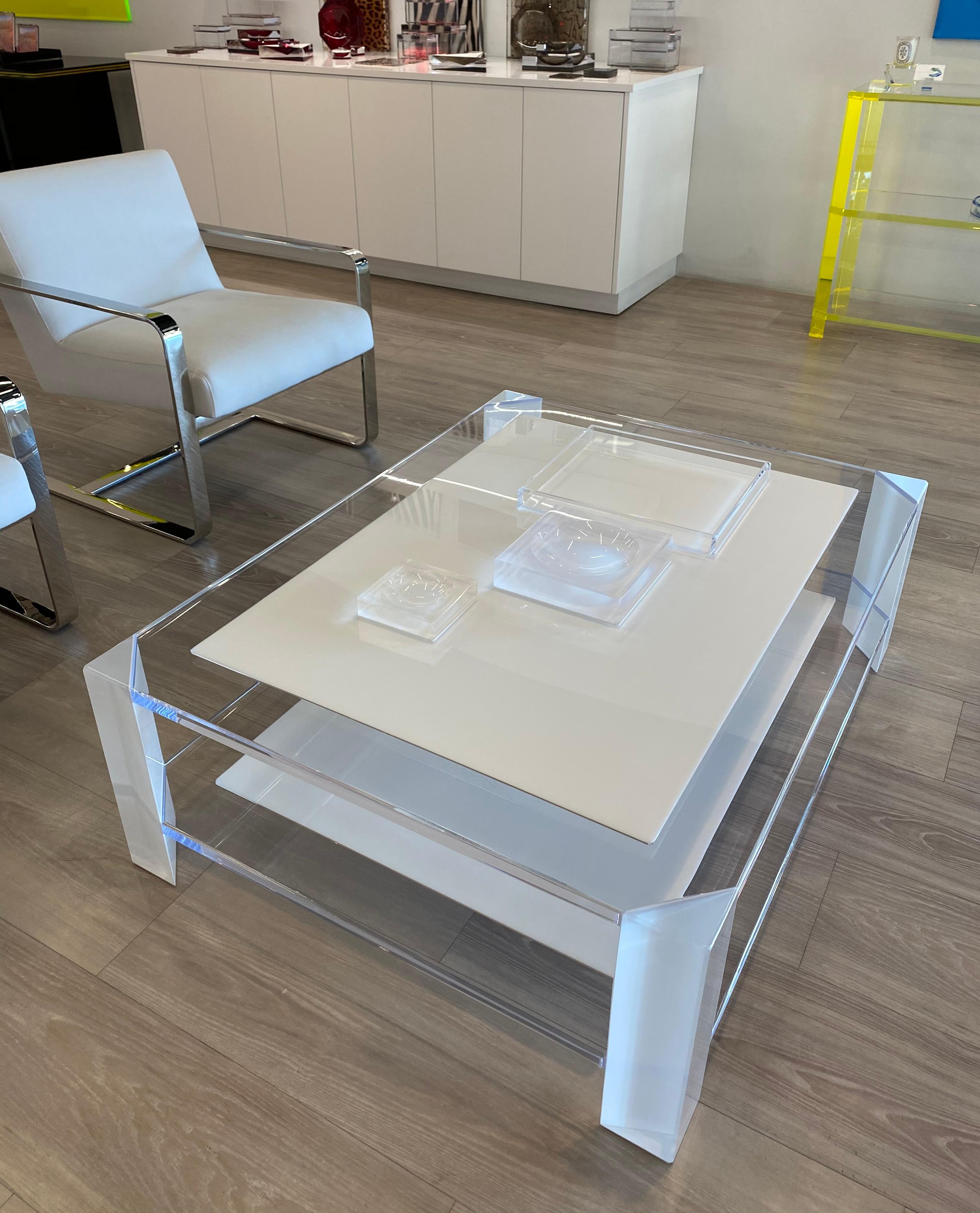 La table basse Sledge d'Alexandra Von Furstenberg, en blanc et lucite transparent, est une pièce d'apparat moderne et élégante. Sa forme classique est complétée par des pieds triangulaires en acrylique transparent avec des accents de blanc. Les