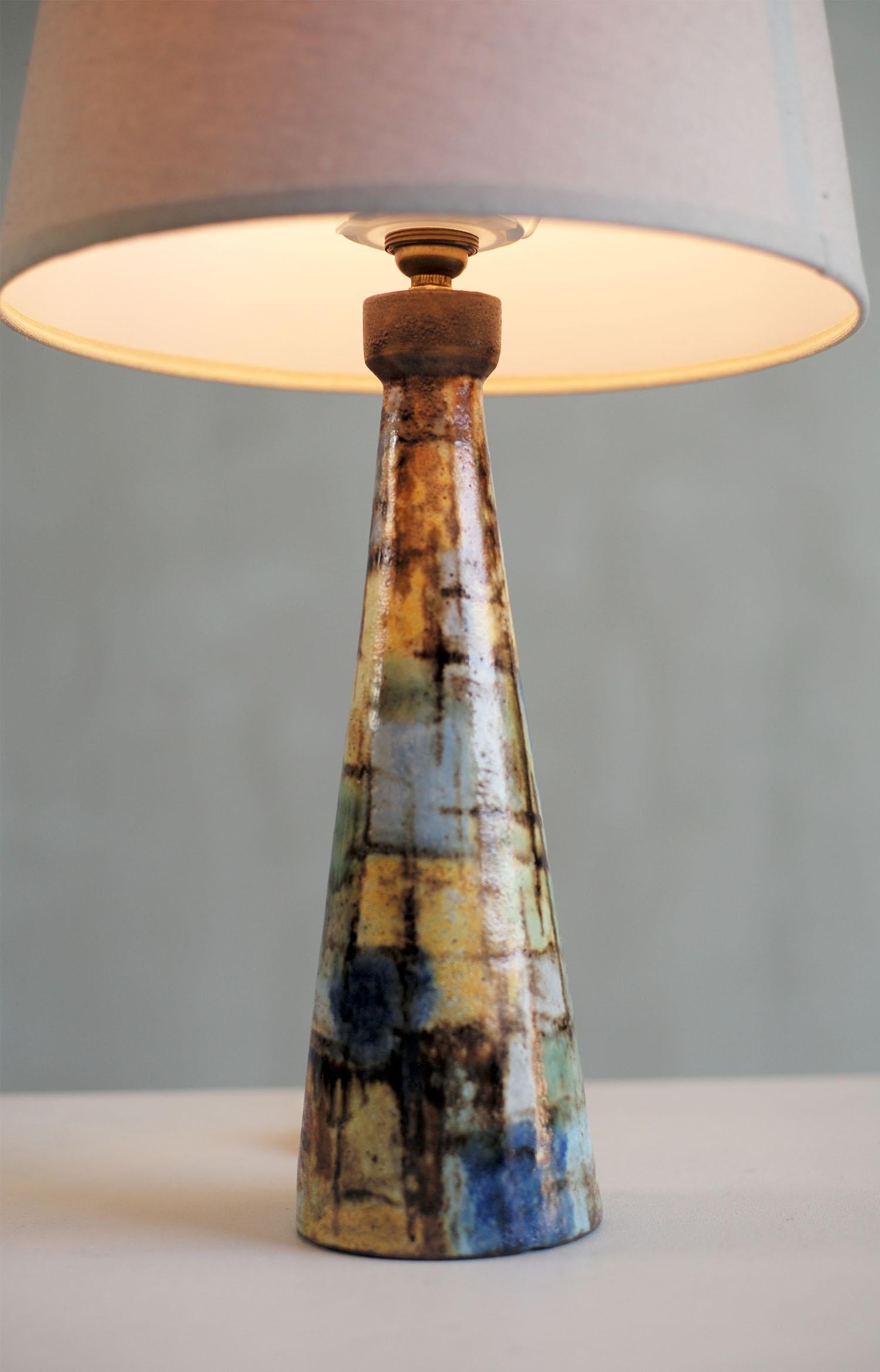 Alexandre Kostanda (1921-2007), Lampe de table en grès émaillé à motifs abstraits, Vallauris 1950. Alternant le bleu clair et l'outremer, le jaune et le vert soulignés par des lignes brunes, ce pied de lampe est signé sous la base. Très bon état.
